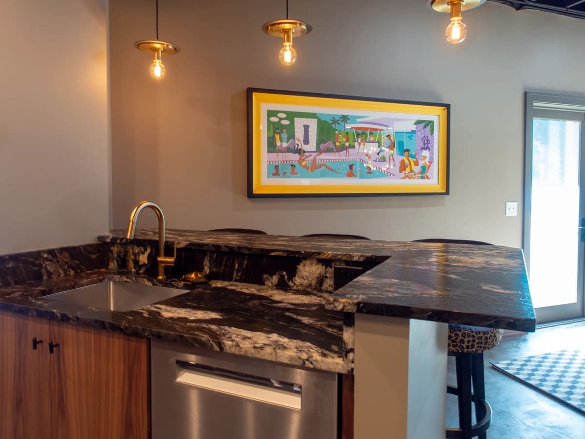 Modern kitchen with marble countertops and a large picture of a beach scene.