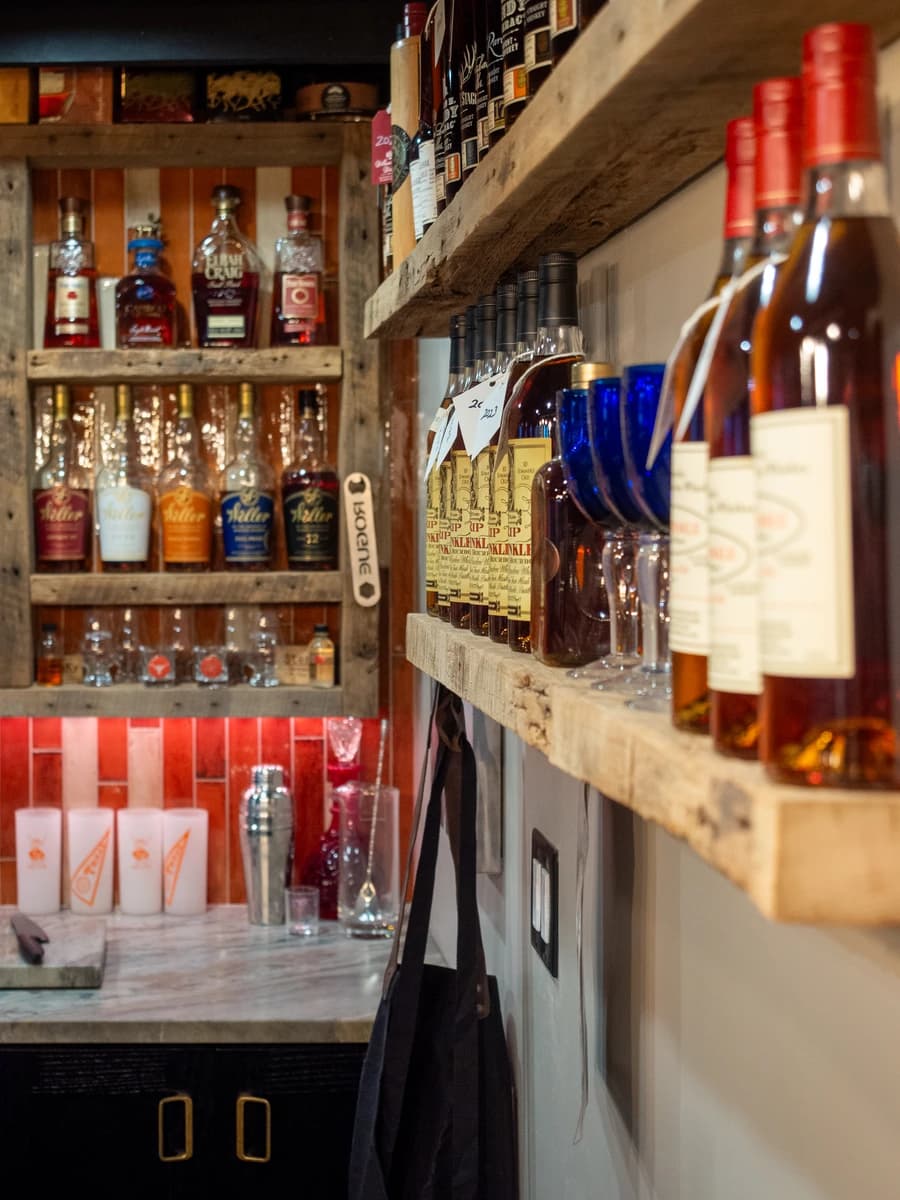 A wooden shelf stocked with a variety of liquor bottles.