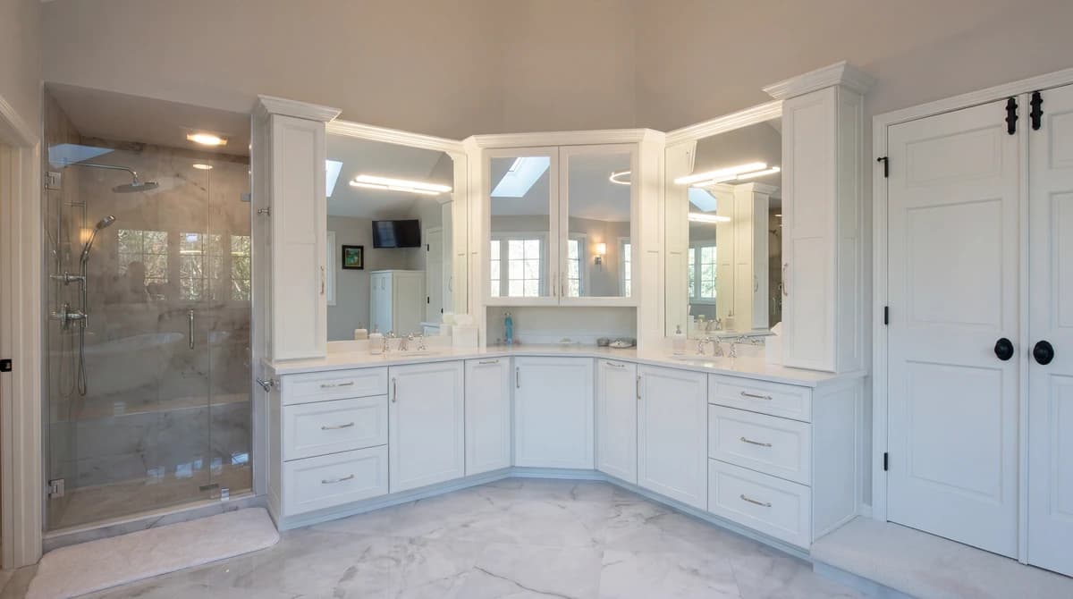 Large bathroom with white cabinets, his and hers sinks, and a large mirror.