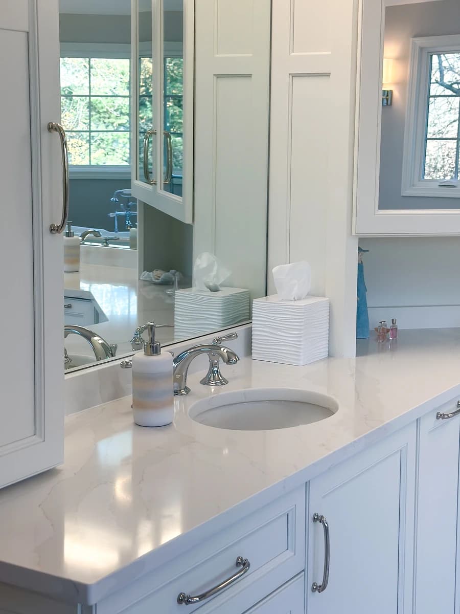 Clean, modern bathroom with white marble countertops, dark wood cabinets, and chrome fixtures.