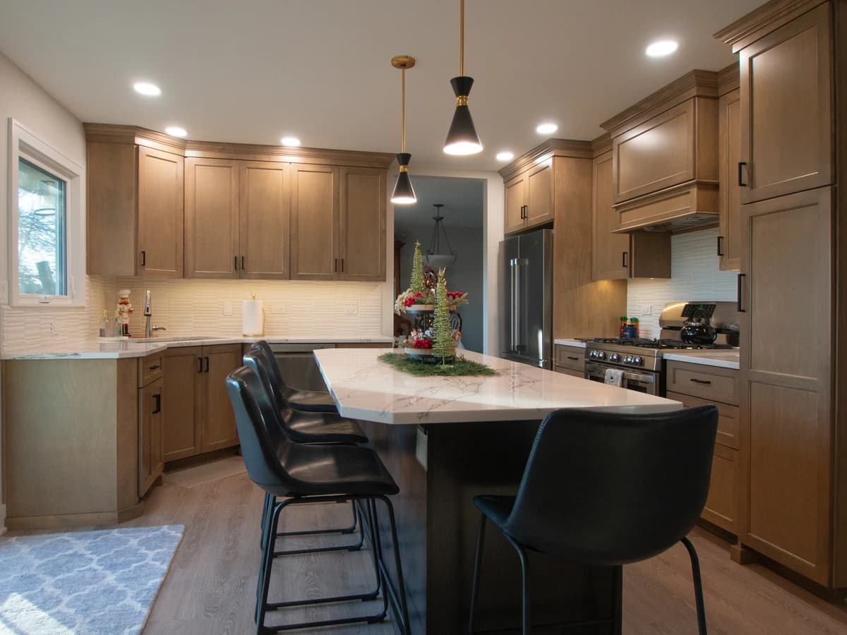Modern kitchen with dark cabinets, stainless appliances, black countertop and large island.