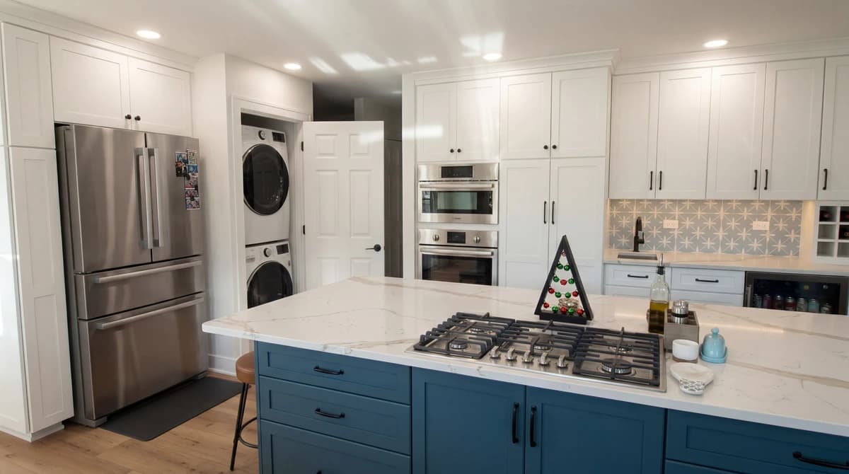 White kitchen with blue cabinets, stainless steel appliances, granite countertops, and white walls.