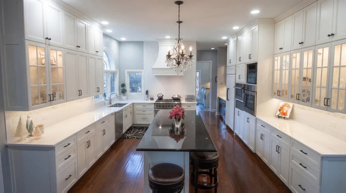 Modern kitchen with white cabinets, black countertops, and large island.