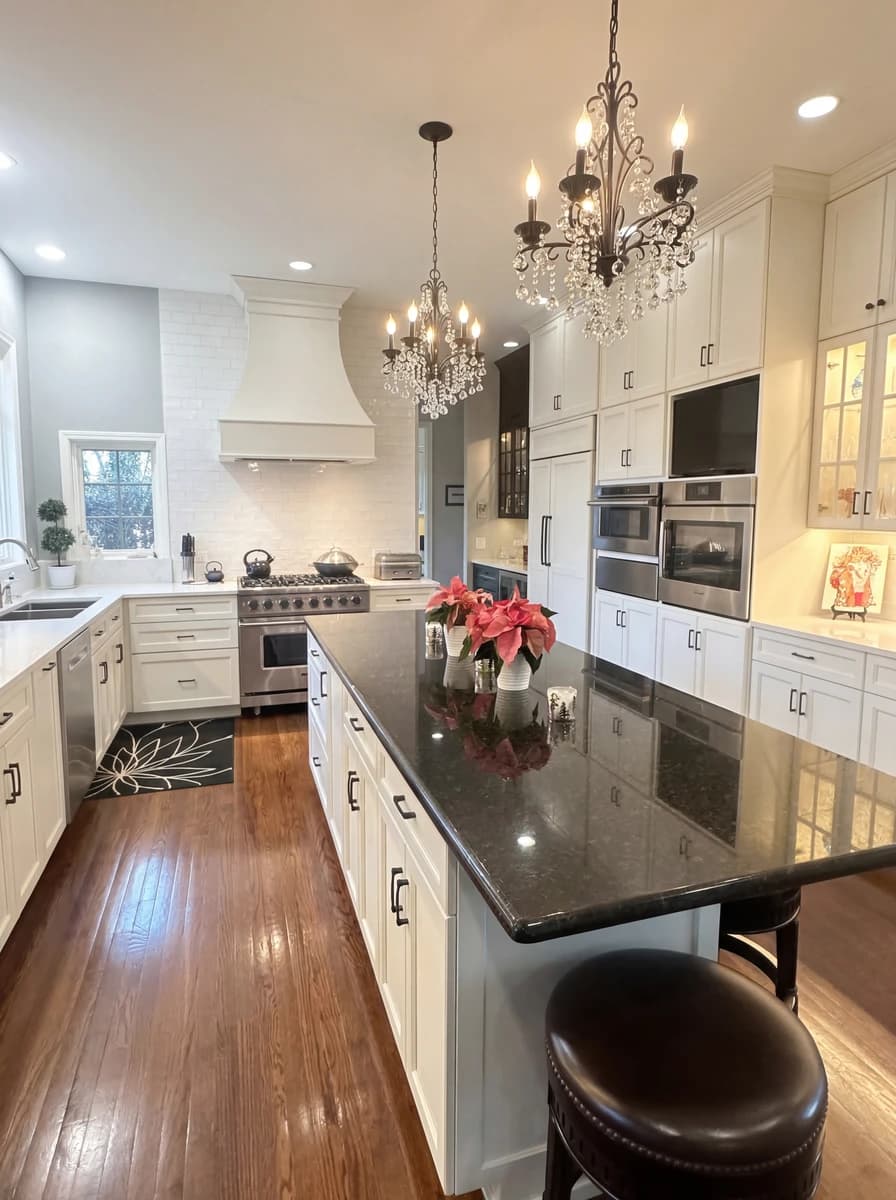 Elegant kitchen with marble counters, chandeliers, and white cabinets.