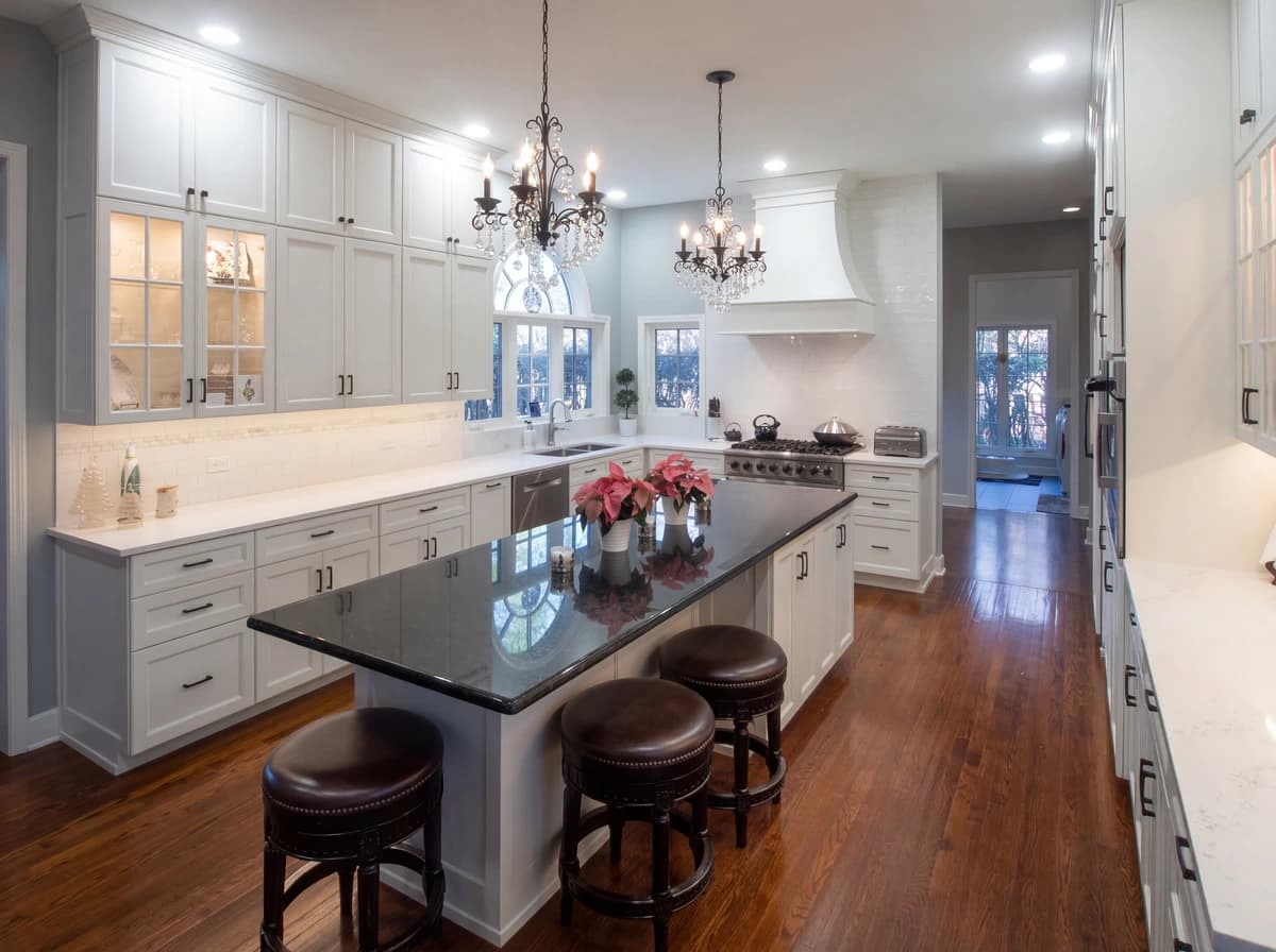 Kitchen with marble counters, white cabinetry, chandelier, island, and hardwood floors.