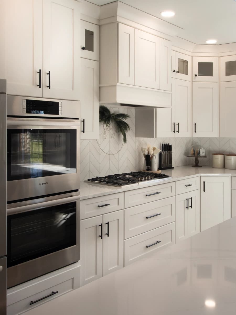 A modern, large kitchen with white cabinets, stainless steel appliances and a center island.