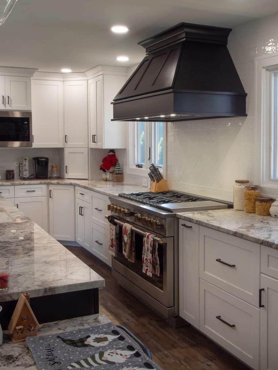 White kitchen cabinets, stainless steel appliances, black hood.