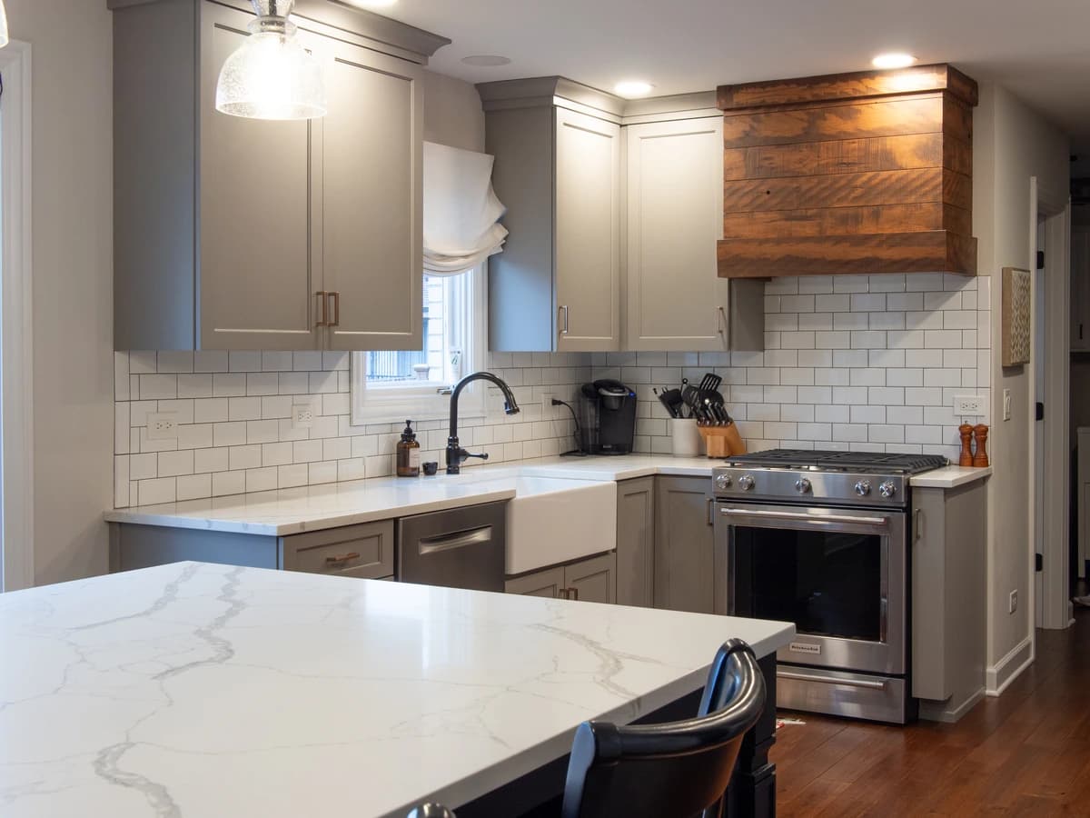 Spacious modern kitchen with white and gray cabinets, marble countertops, chrome appliances, and a