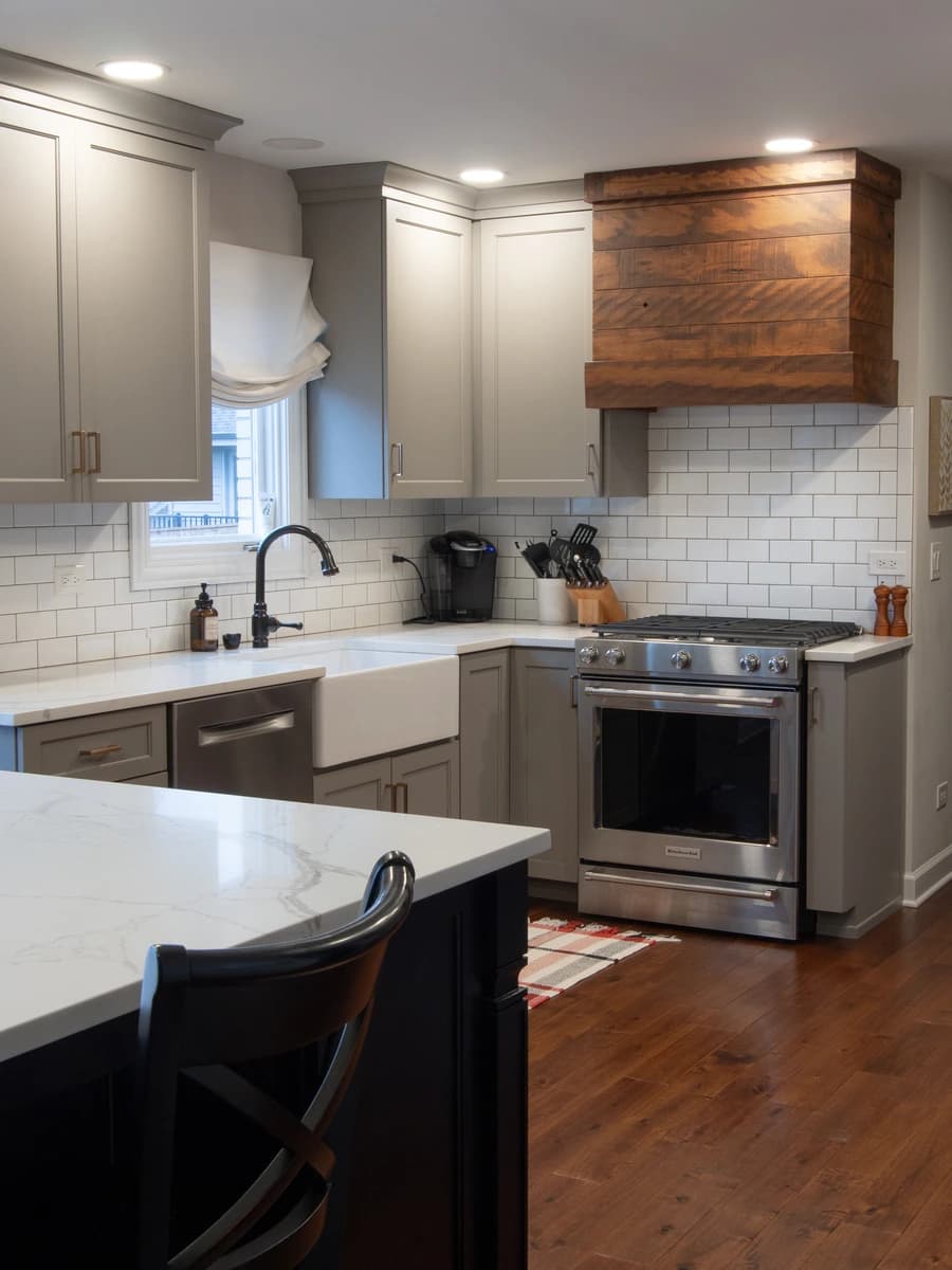 Large kitchen with silver stove, marble countertops, white cabinets, and grey walls.
