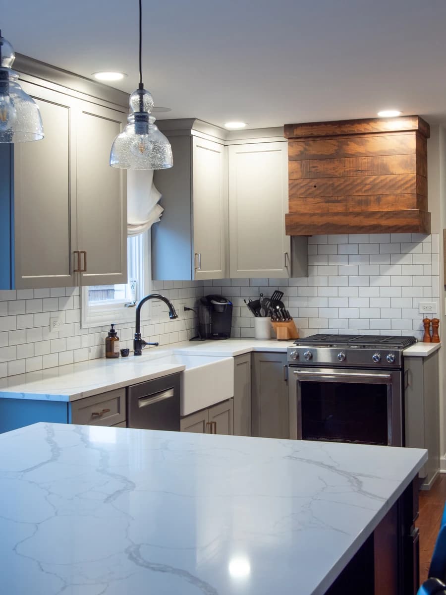 Modern kitchen with white marble countertops and stainless steel appliances.