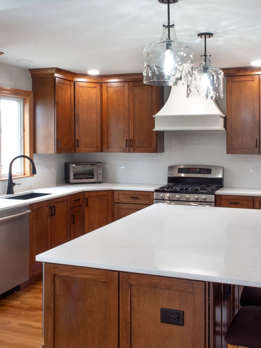 The kitchen features dark brown cabinets, white countertops, and stainless steel appliances.