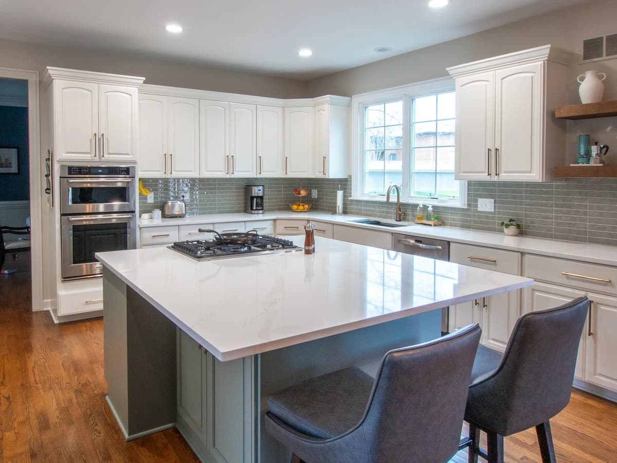 Modern kitchen with white cabinets and marble countertops.