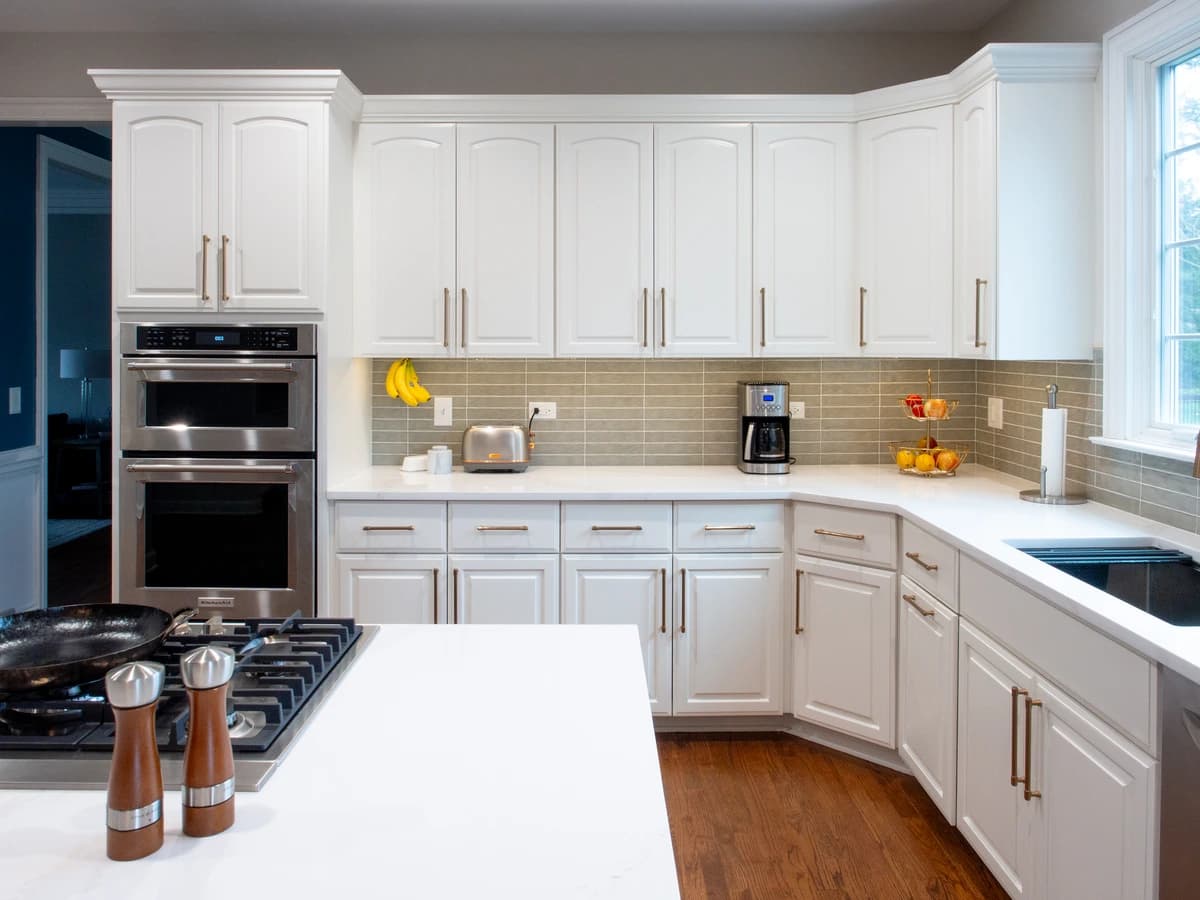Large, modern kitchen with white cabinetry, black countertops, and tan trim.