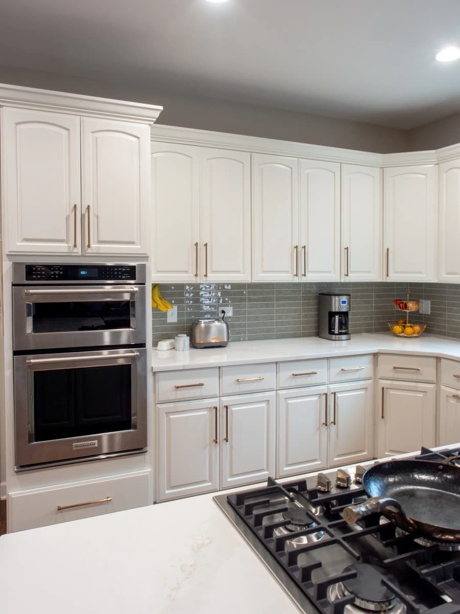 Modern kitchen with white cabinets and stainless steel appliances.