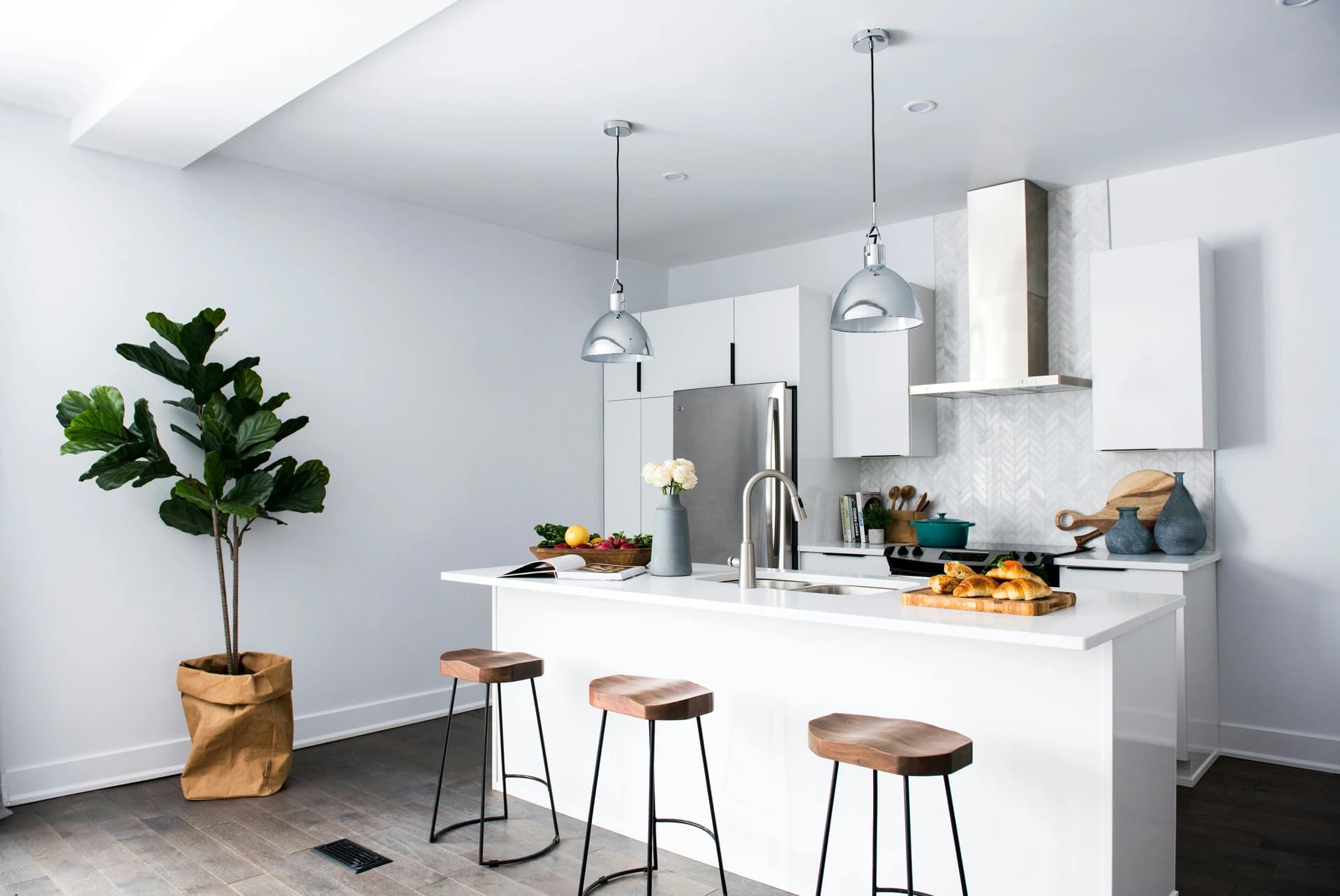 Bright kitchen with a white island and hanging pendant lights.