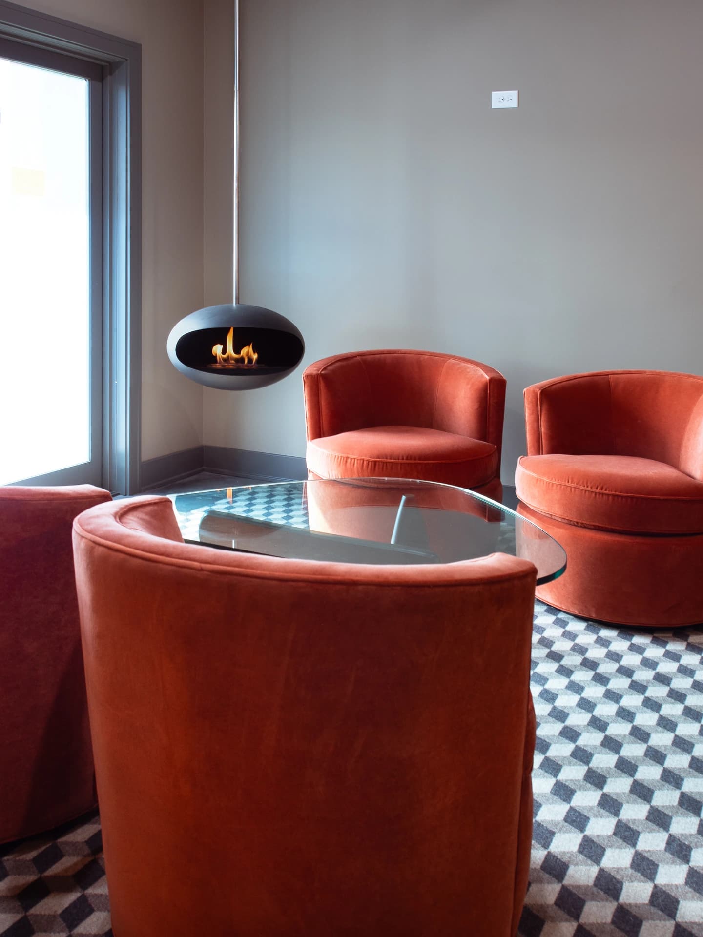 A modern living room with a red sofa, a white and black geometric rug, and red chairs.