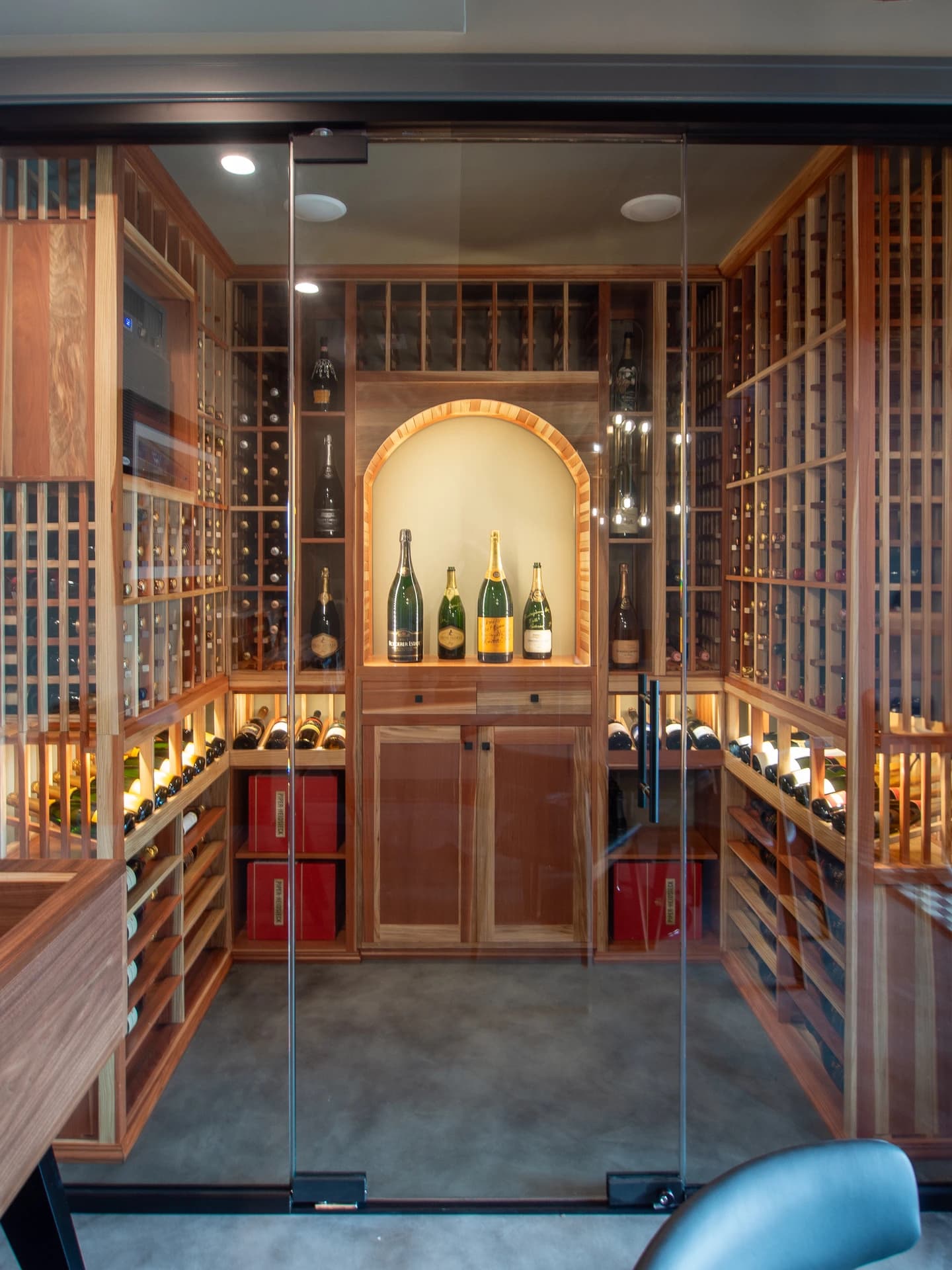 Luxurious wine cellar with a glass wall, filled with bottles and wooden wine rack.