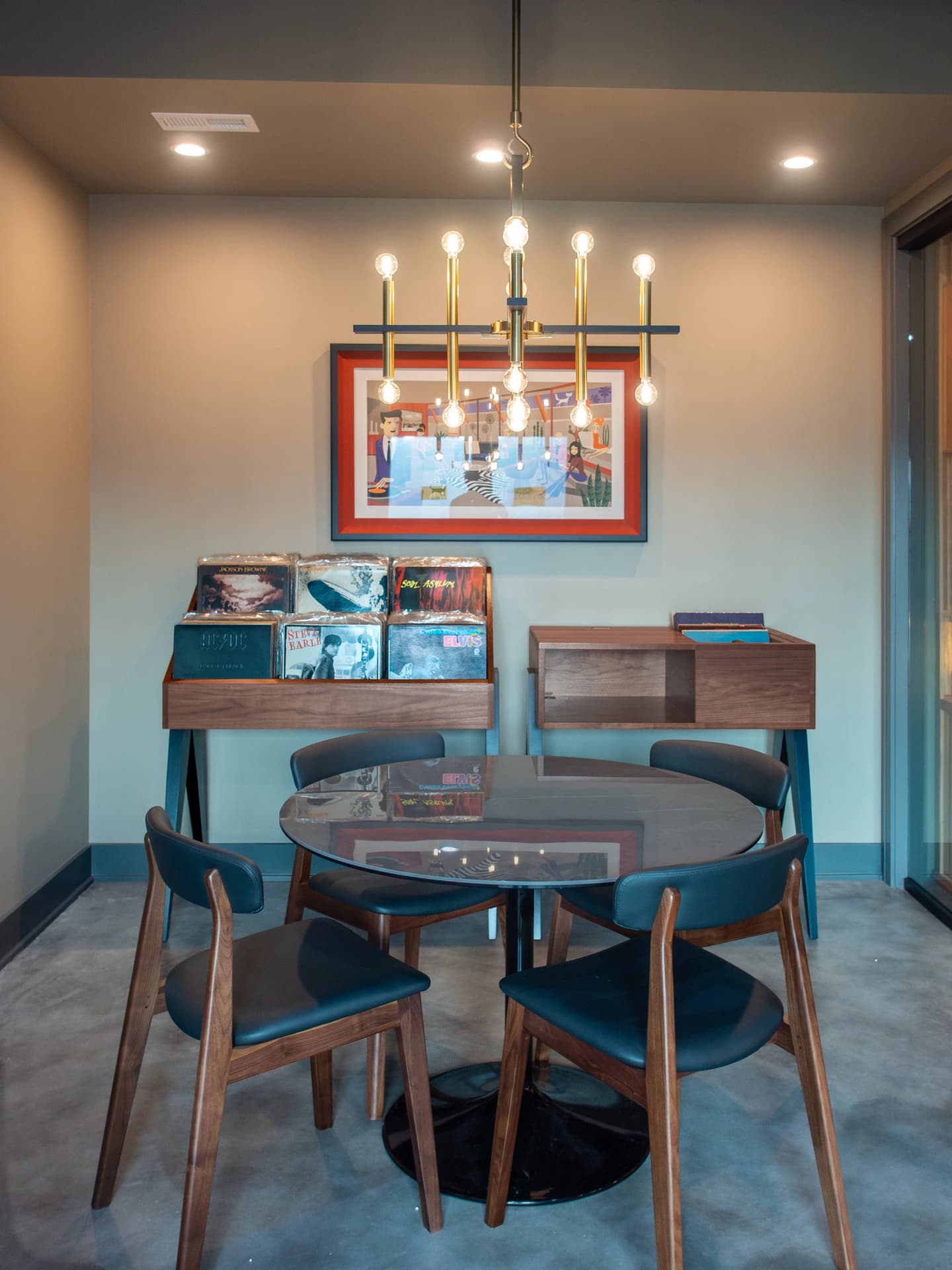 Modern dining room with a wood floor, chandelier, blue chairs, and a contemporary table.