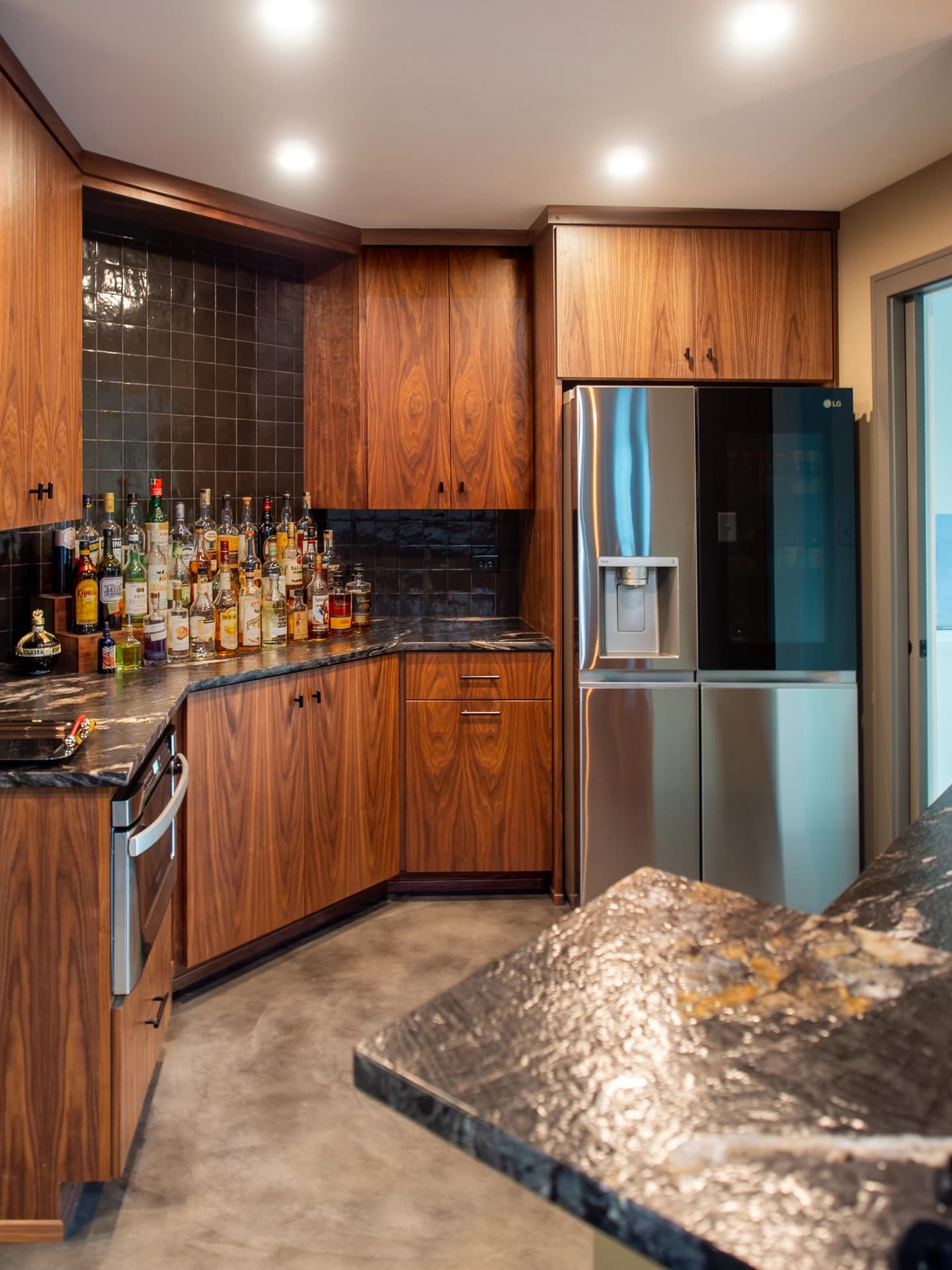 Modern kitchen with wooden cabinetry, marble countertops, stainless steel appliances.