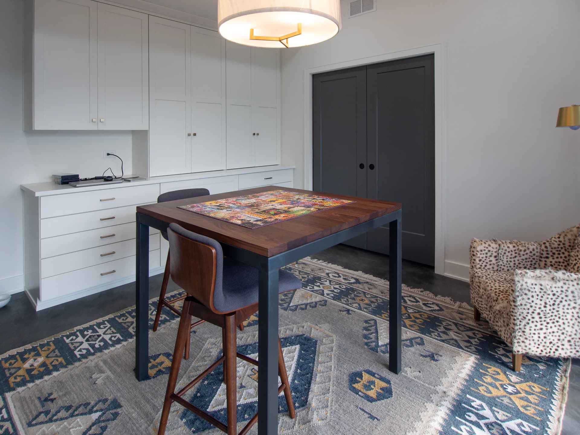 White kitchen with wooden island, metal stools, white cabinets, and patterned rug.
