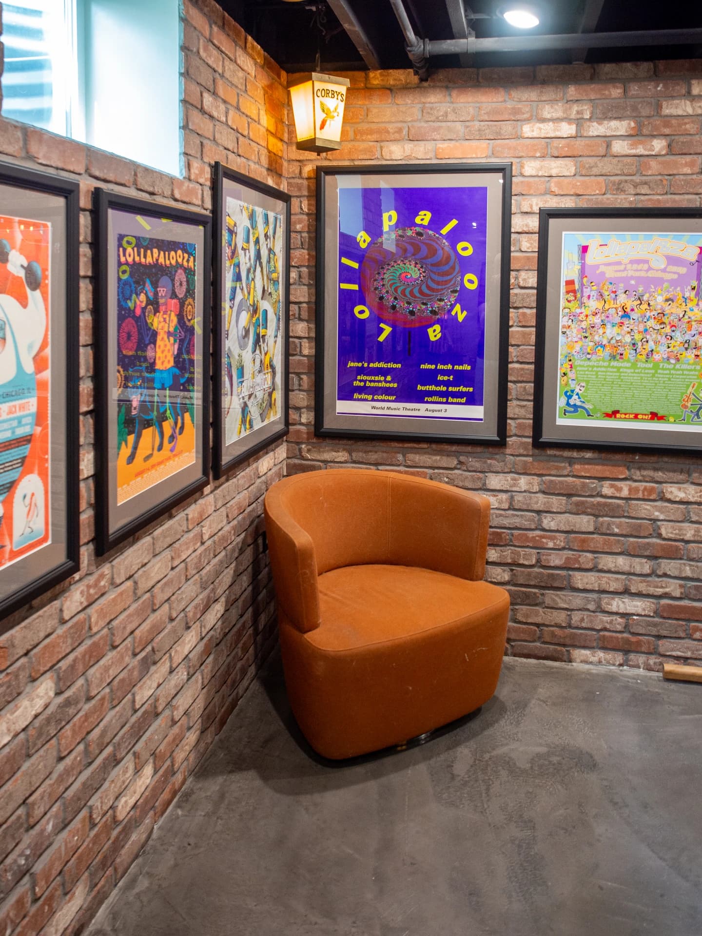 A room with brick walls, framed art, a red chair, and a colorful abstract painting.