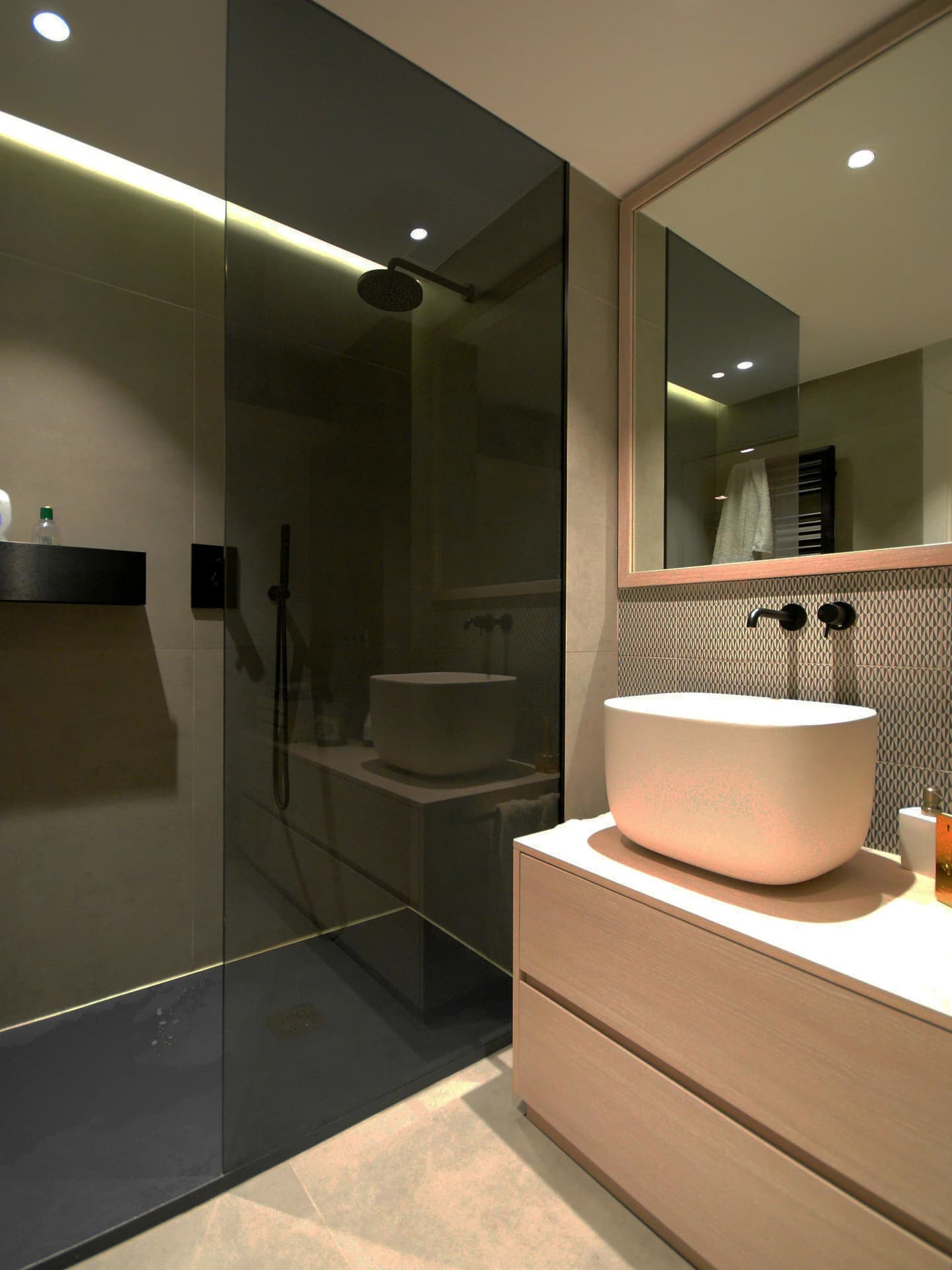 Modern bathroom with sleek dark glass shower, wood vanity, and neutral color palette.
