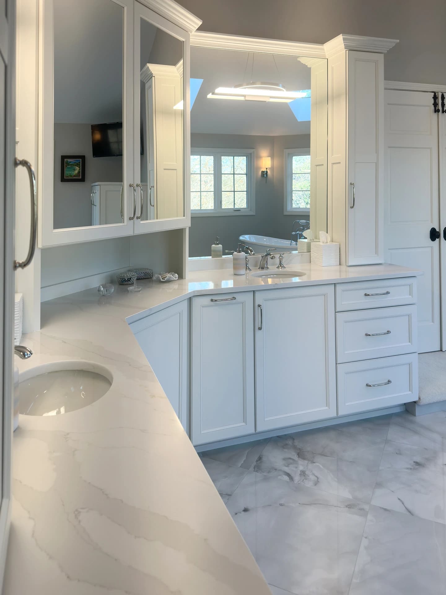 Modern bathroom with white marble countertop, marble floor, and wooden cabinets.