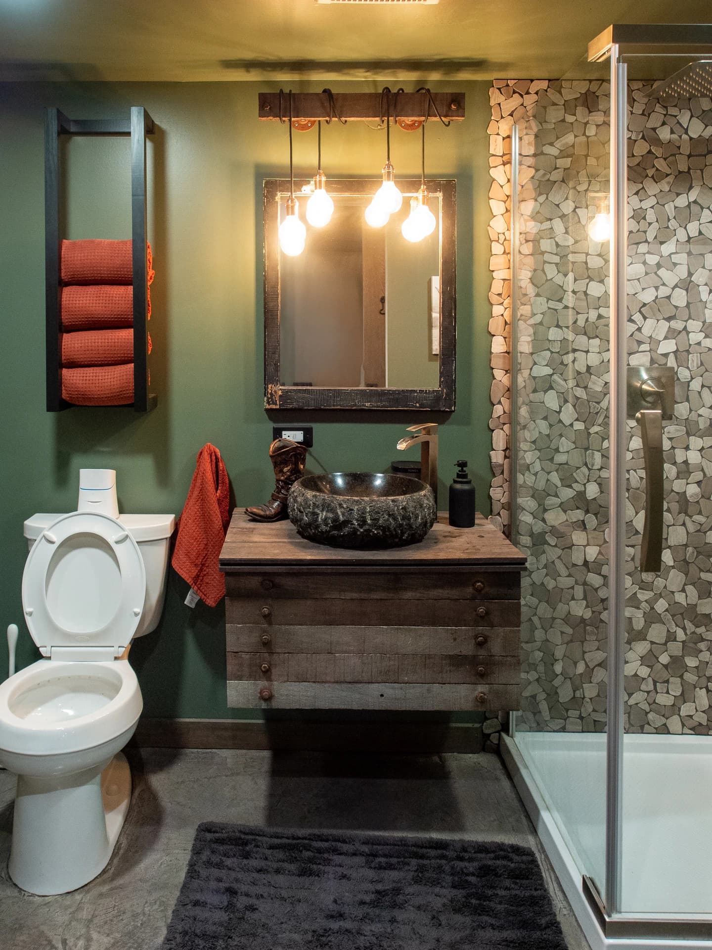 A bathroom with a green and brown accent wall, a vanity, a toilet, and a sink.