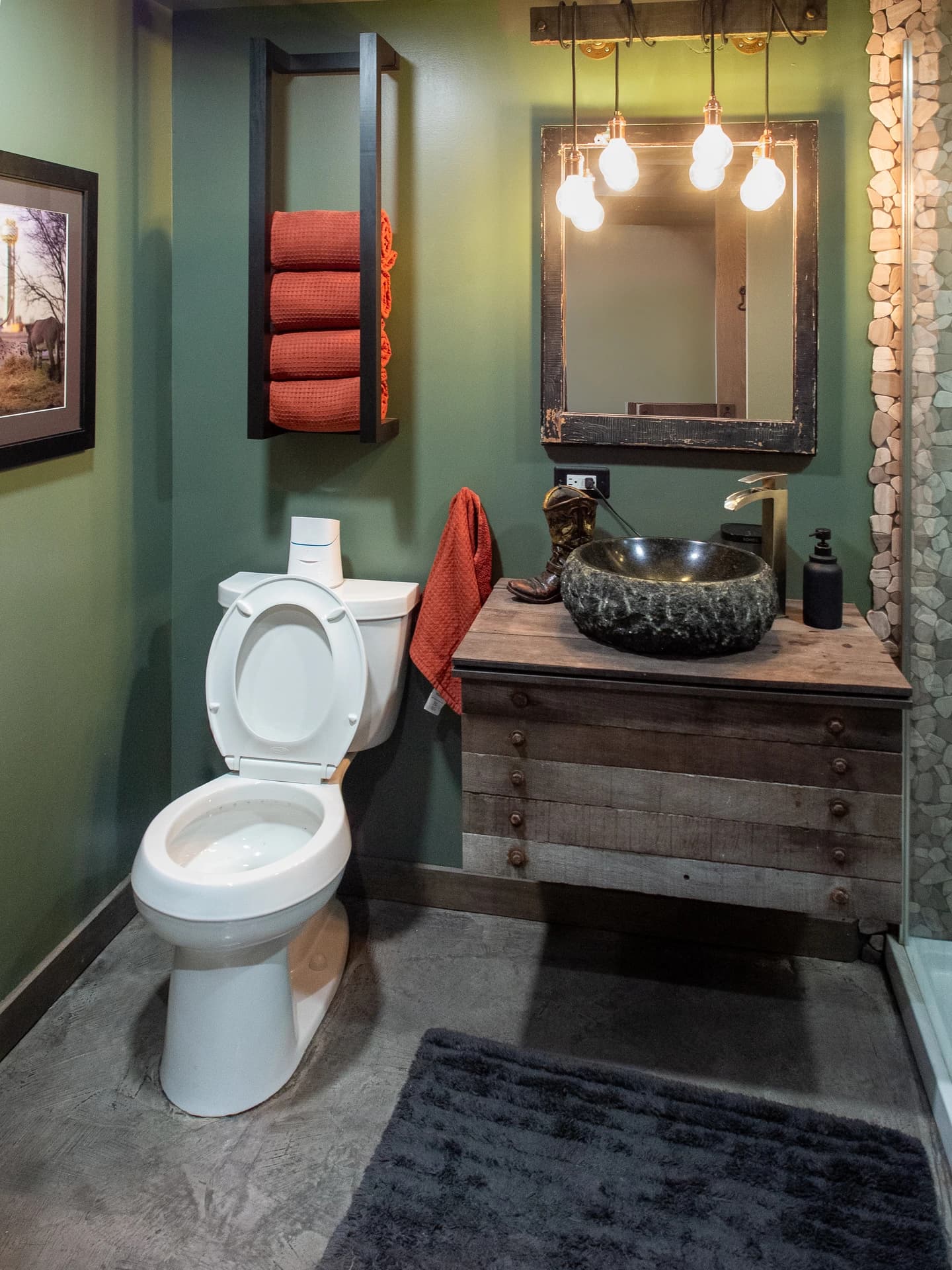 Bathroom with dark green walls, white toilet, red rug, and a sink with mirror.