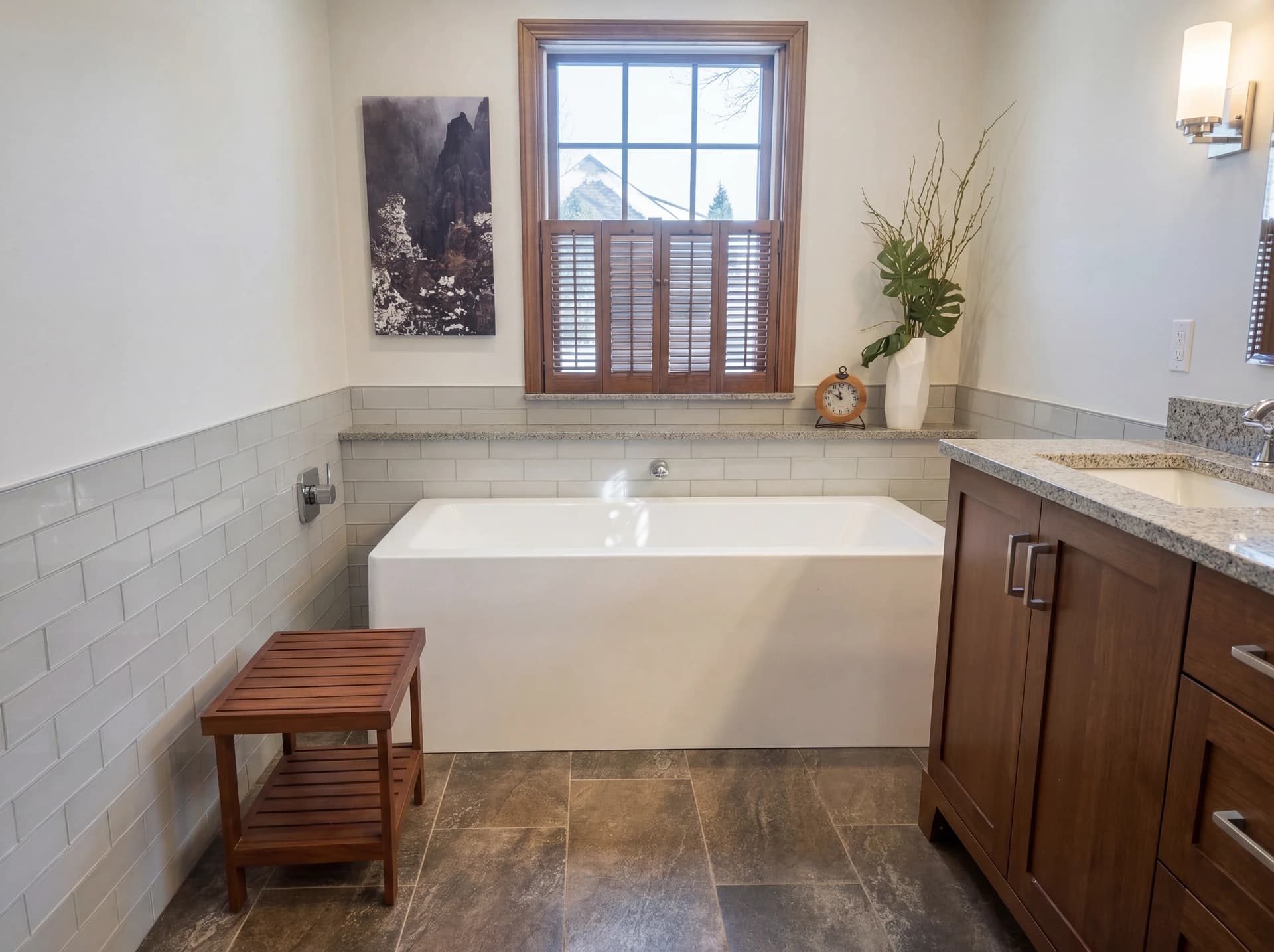 Modern bathroom with white subway tiles, wooden bench, large mirror, beige counter, and tiled floor.