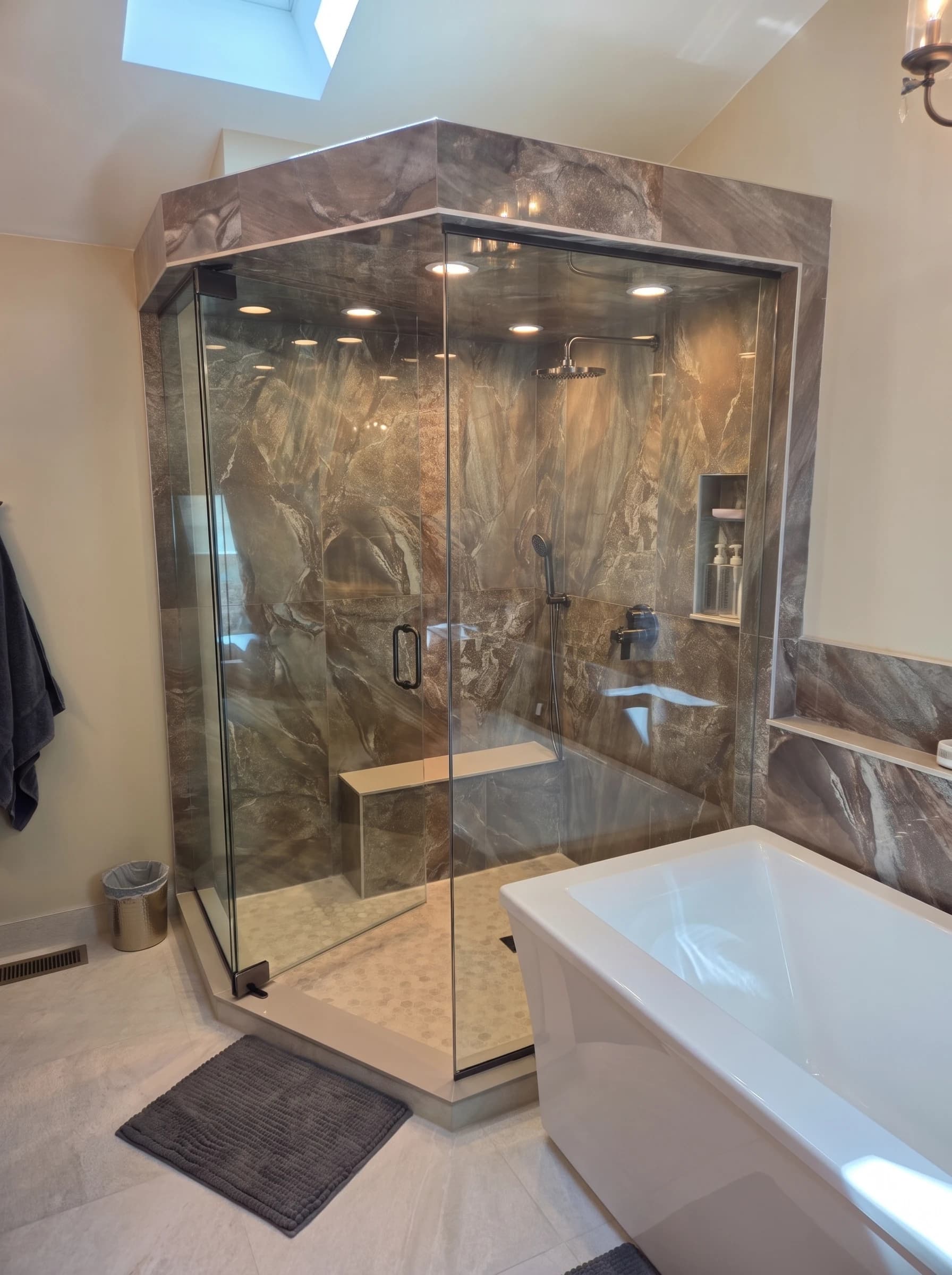 Neo-angle glass walk-in shower with dramatic marble-pattern walls, rainfall showerhead, and freestanding soaking tub.