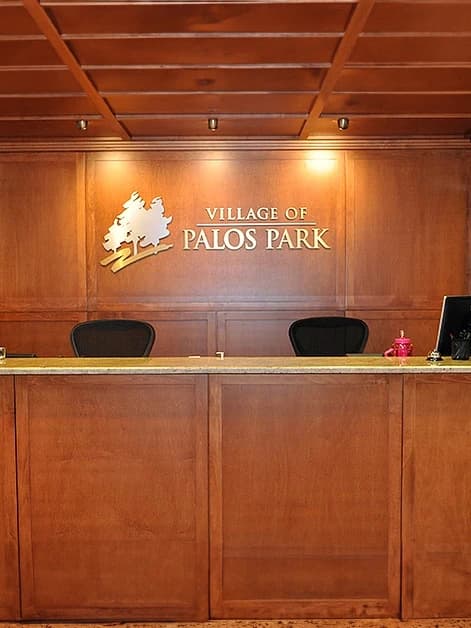 A wooden desk with a village of palos park sign on it.