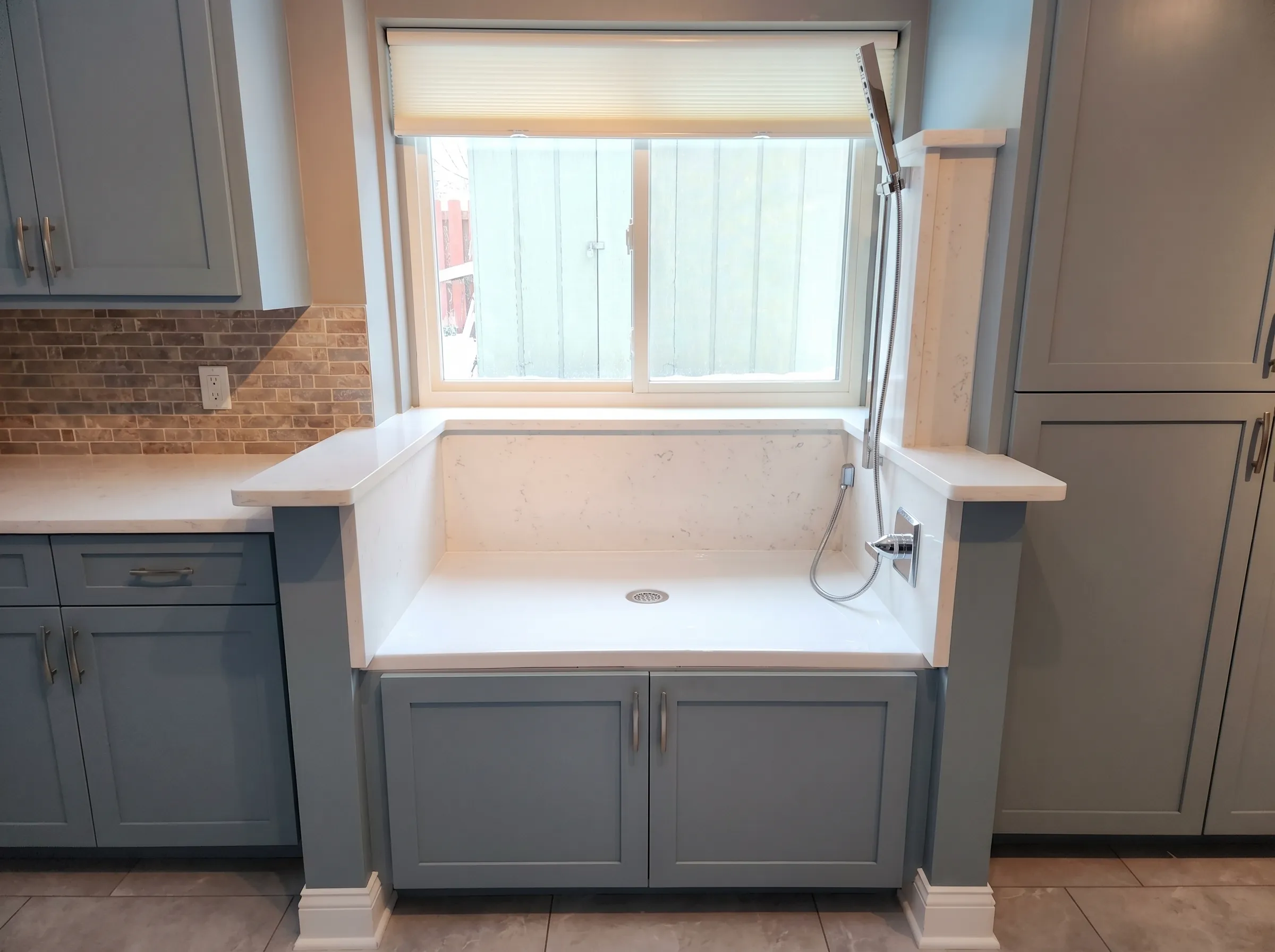 Blue kitchen cabinets with double sink and white countertop.