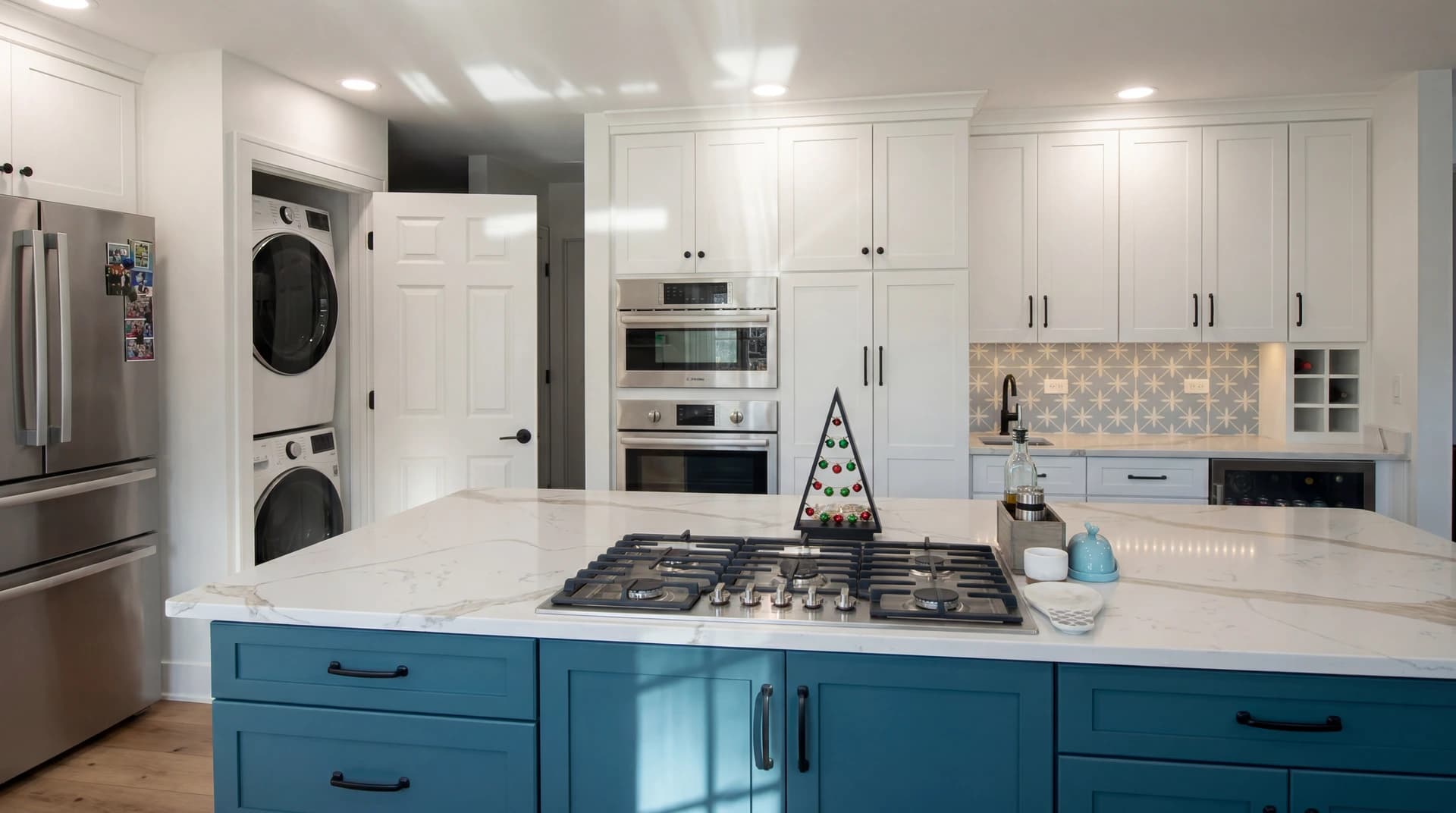 A modern kitchen with light oak cabinets, white appliances, and blue island.