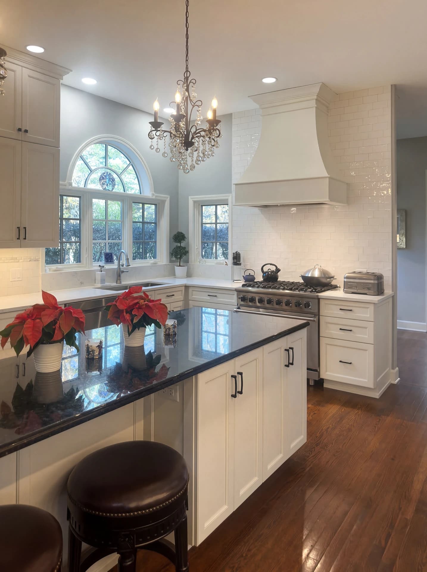 Modern kitchen with white cabinets, black countertop, white stove, and black chandelier.