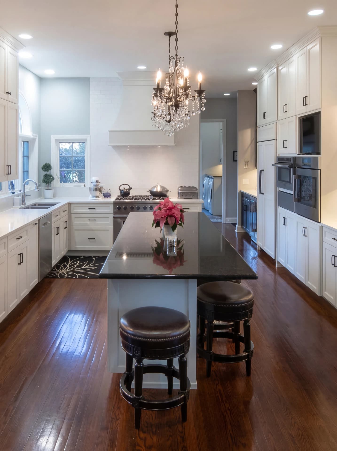 Modern kitchen with stainless steel appliances, dark wooden flooring, and white cabinetry.