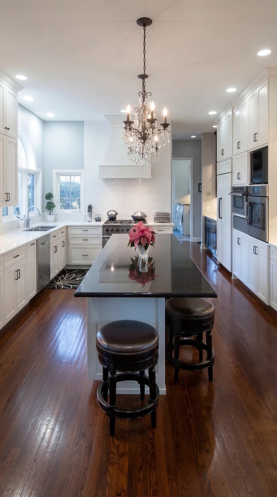 A bright and modern kitchen with a center island, dark wood flooring, and white cabinetry.