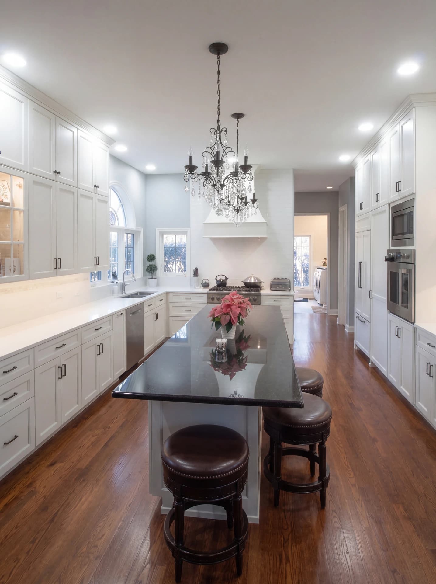 A modern kitchen with white cabinets, dark wood flooring, and a large island in the center.