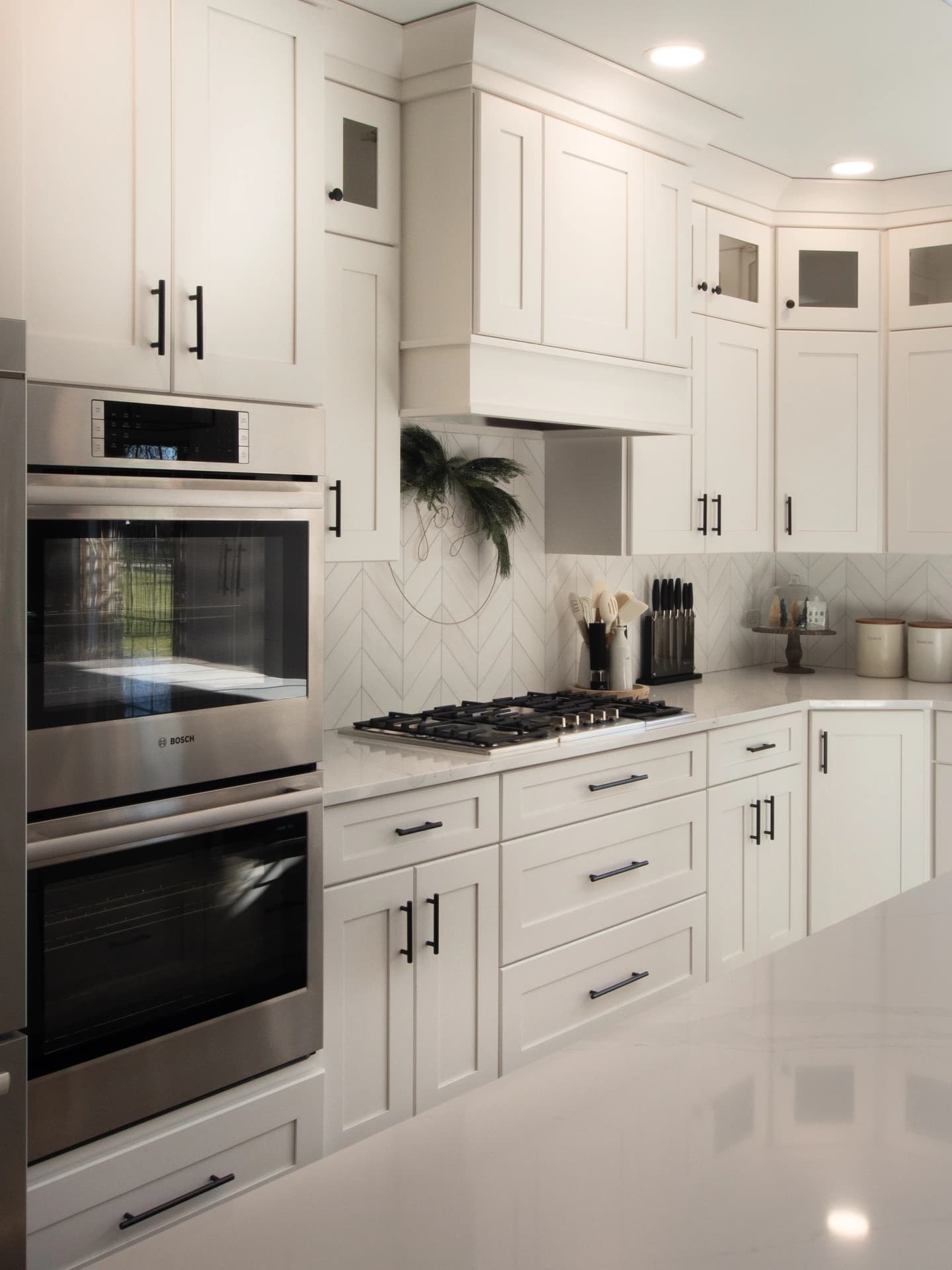 A modern, large kitchen with white cabinets, stainless steel appliances and a center island.