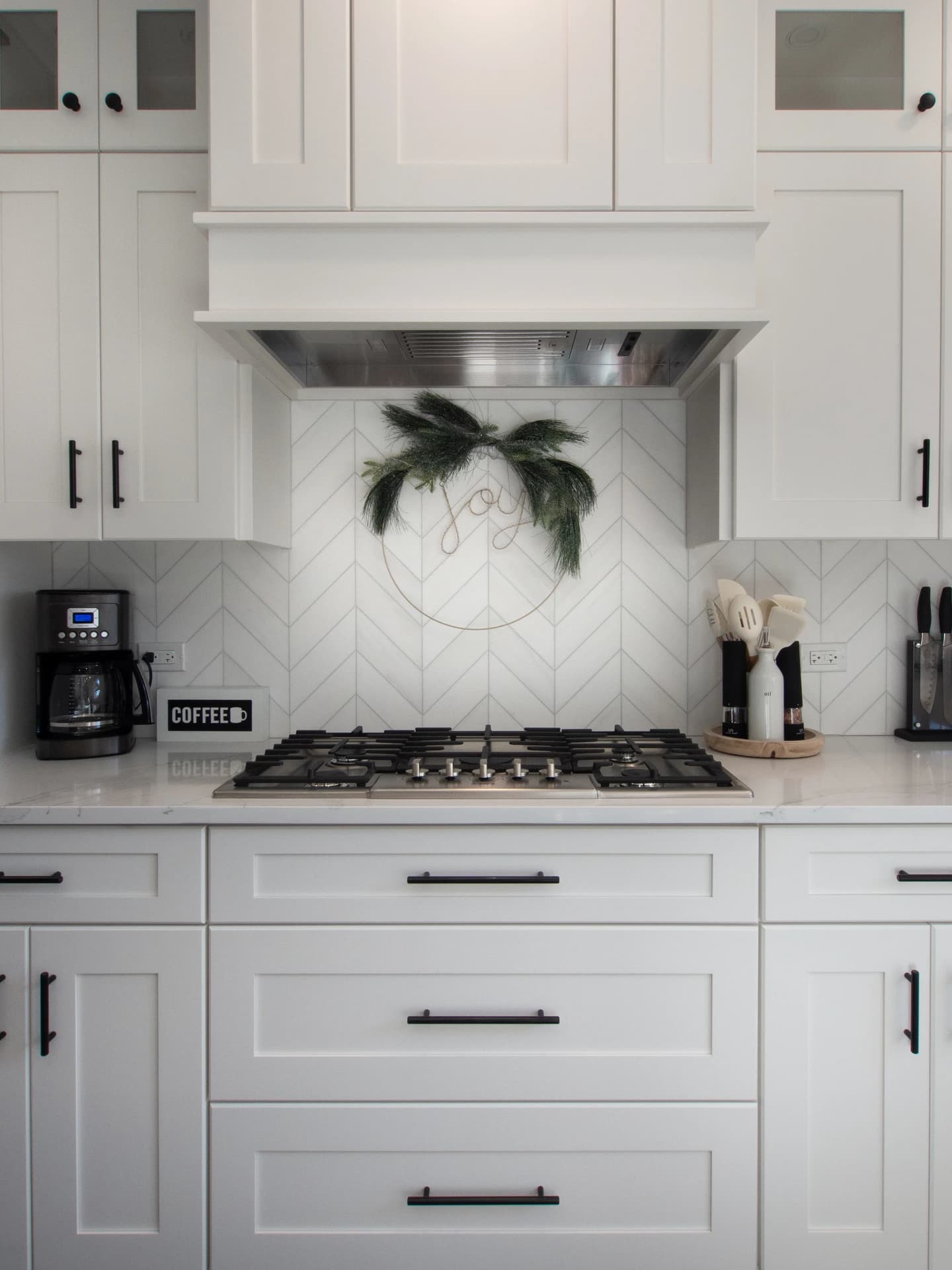 A modern kitchen with white cabinets, black appliances, white tile backsplash, and a large island.