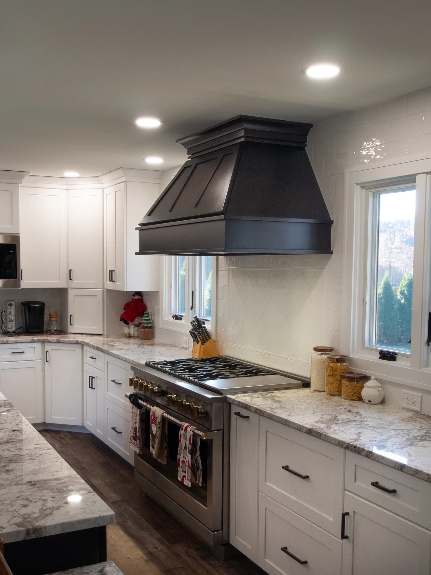 Clean, modern kitchen with white cabinets, stainless steel appliances, and a black vent hood.