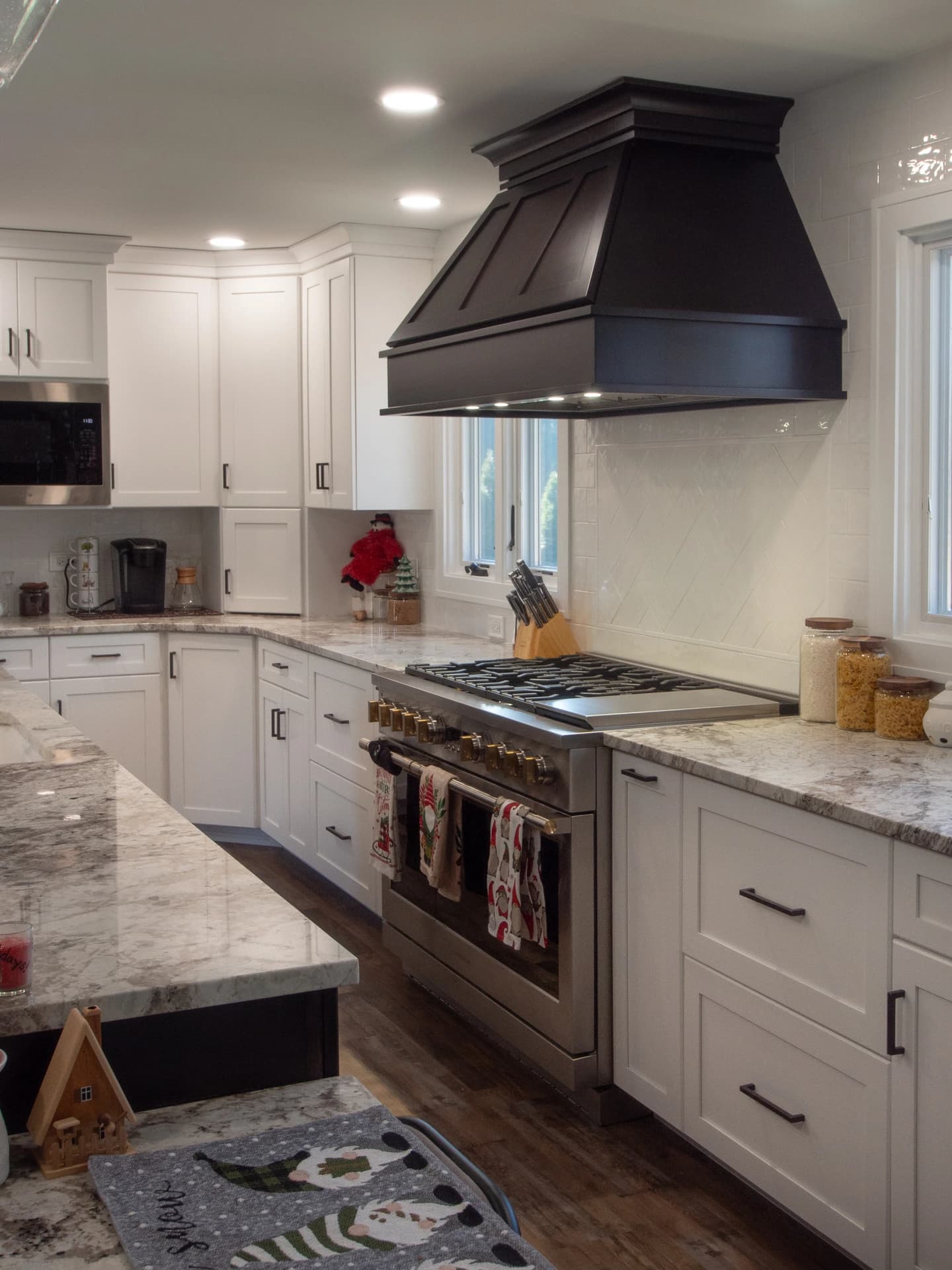 White kitchen cabinets, stainless steel appliances, black hood.