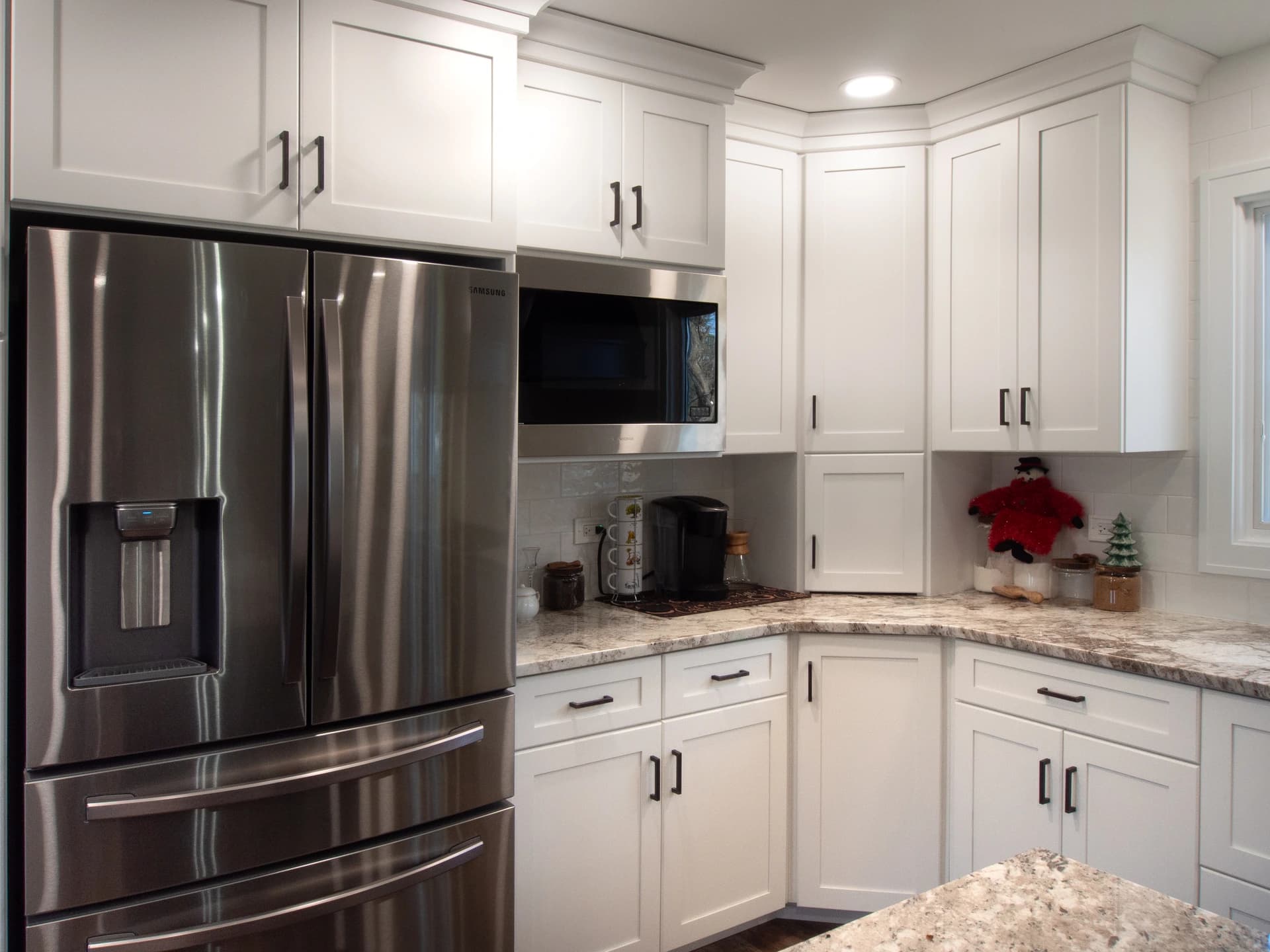 White kitchen cabinets with chrome hardware and stainless steel appliances.