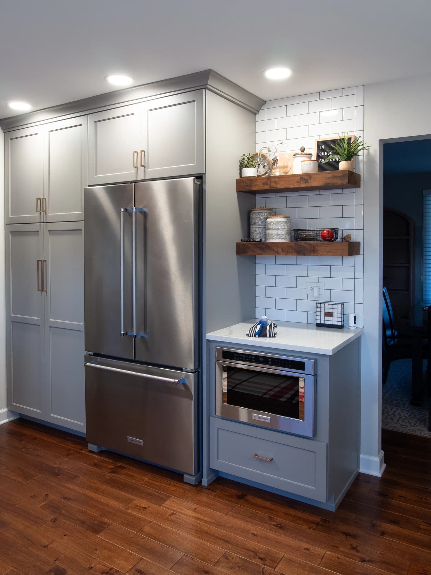 Modern kitchen with stainless steel appliances, silver cabinets, and white subway tiles.