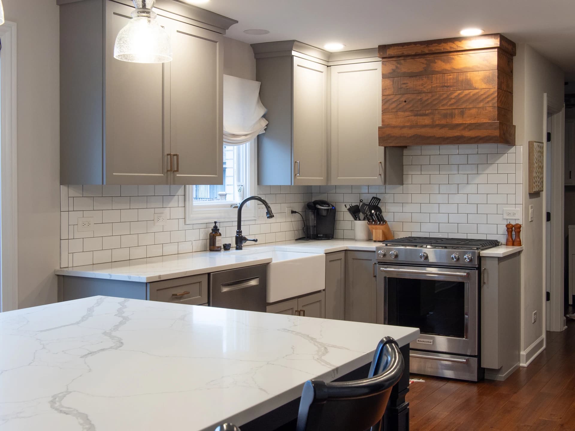 Spacious modern kitchen with white and gray cabinets, marble countertops, chrome appliances, and a