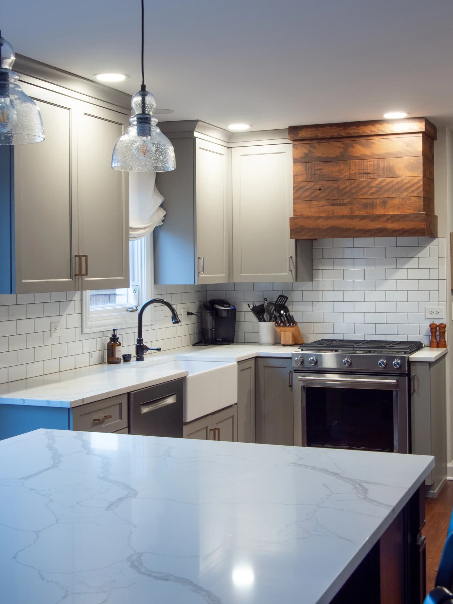 Modern kitchen with white marble countertops and stainless steel appliances.