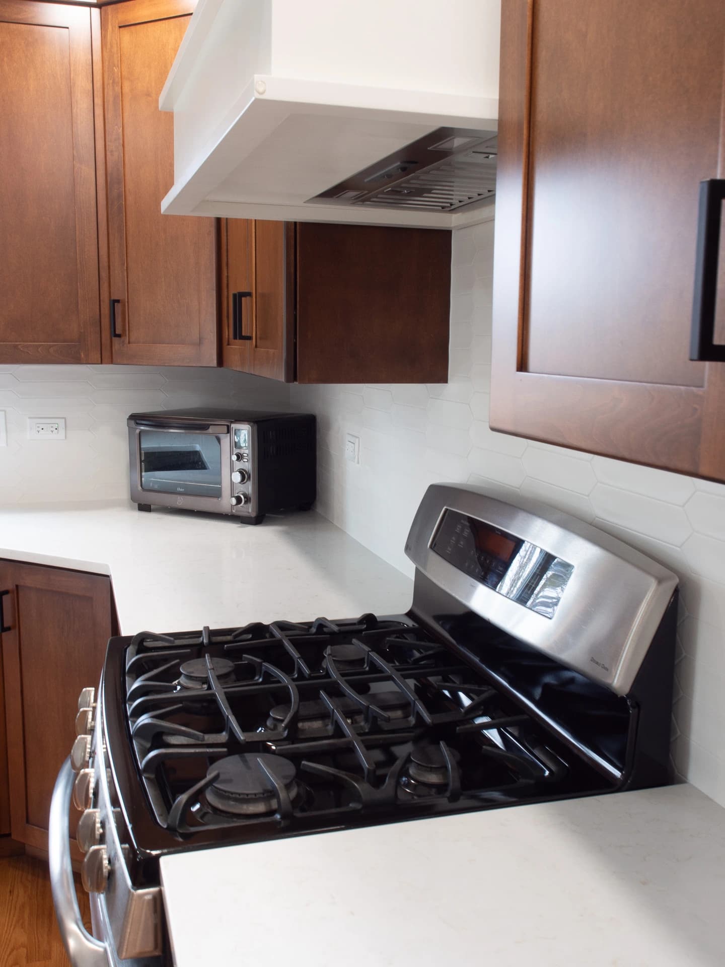 Modern kitchen with wooden cabinets, stainless steel appliances, and white backsplash.