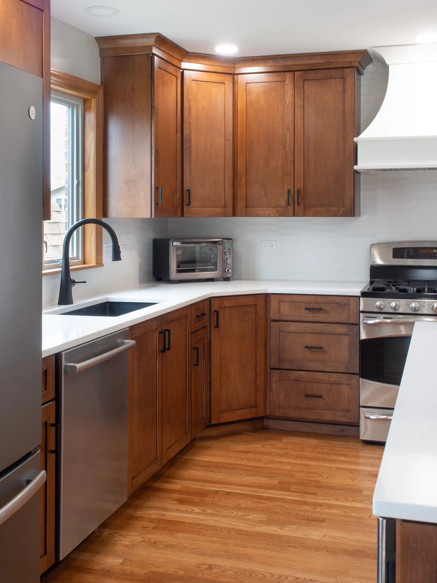 Modern kitchen with stainless steel appliances, wooden cabinets, and a black countertop.