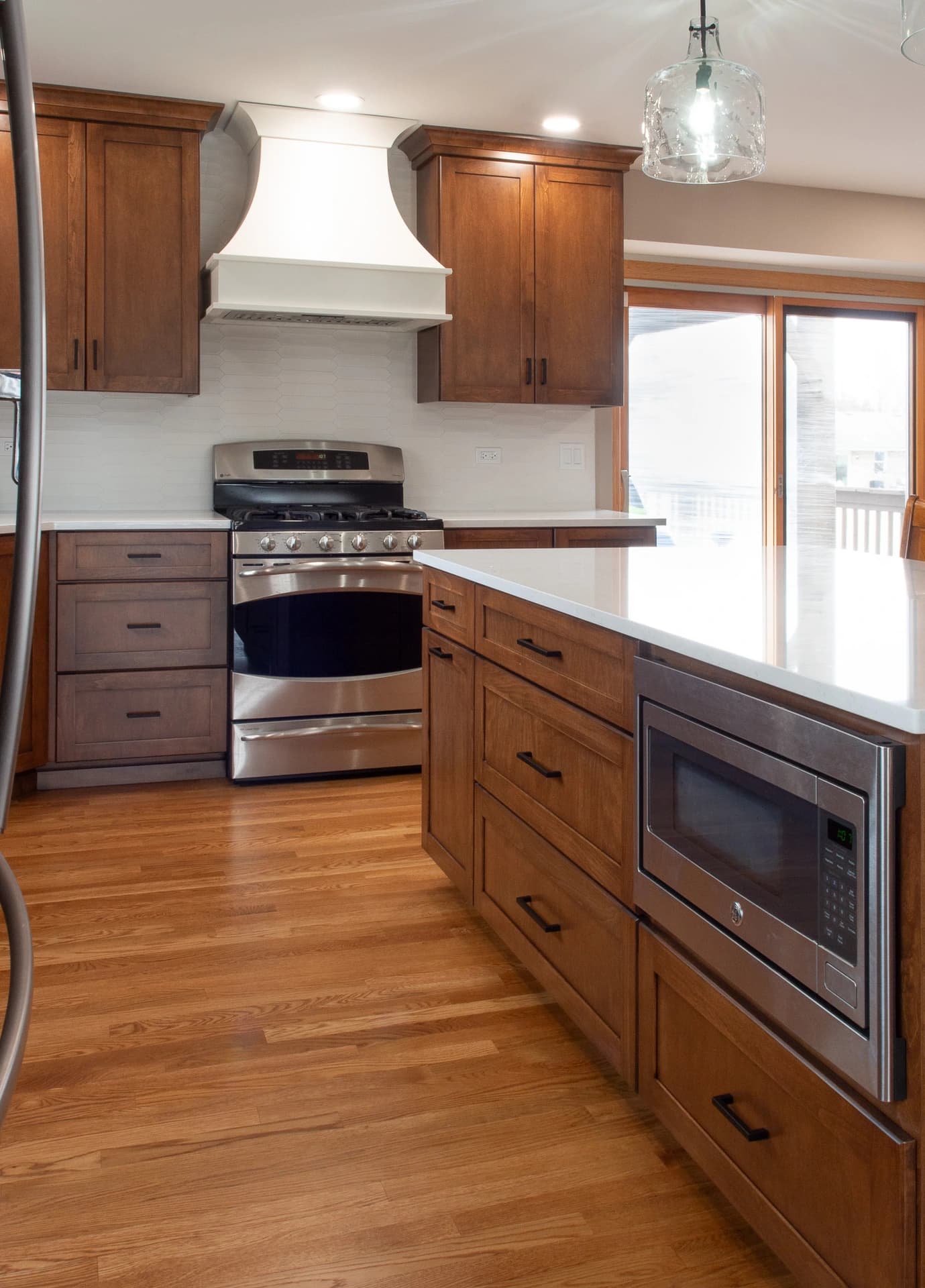 Modern kitchen with dark wood cabinets, stainless steel appliances, and a white countertop.