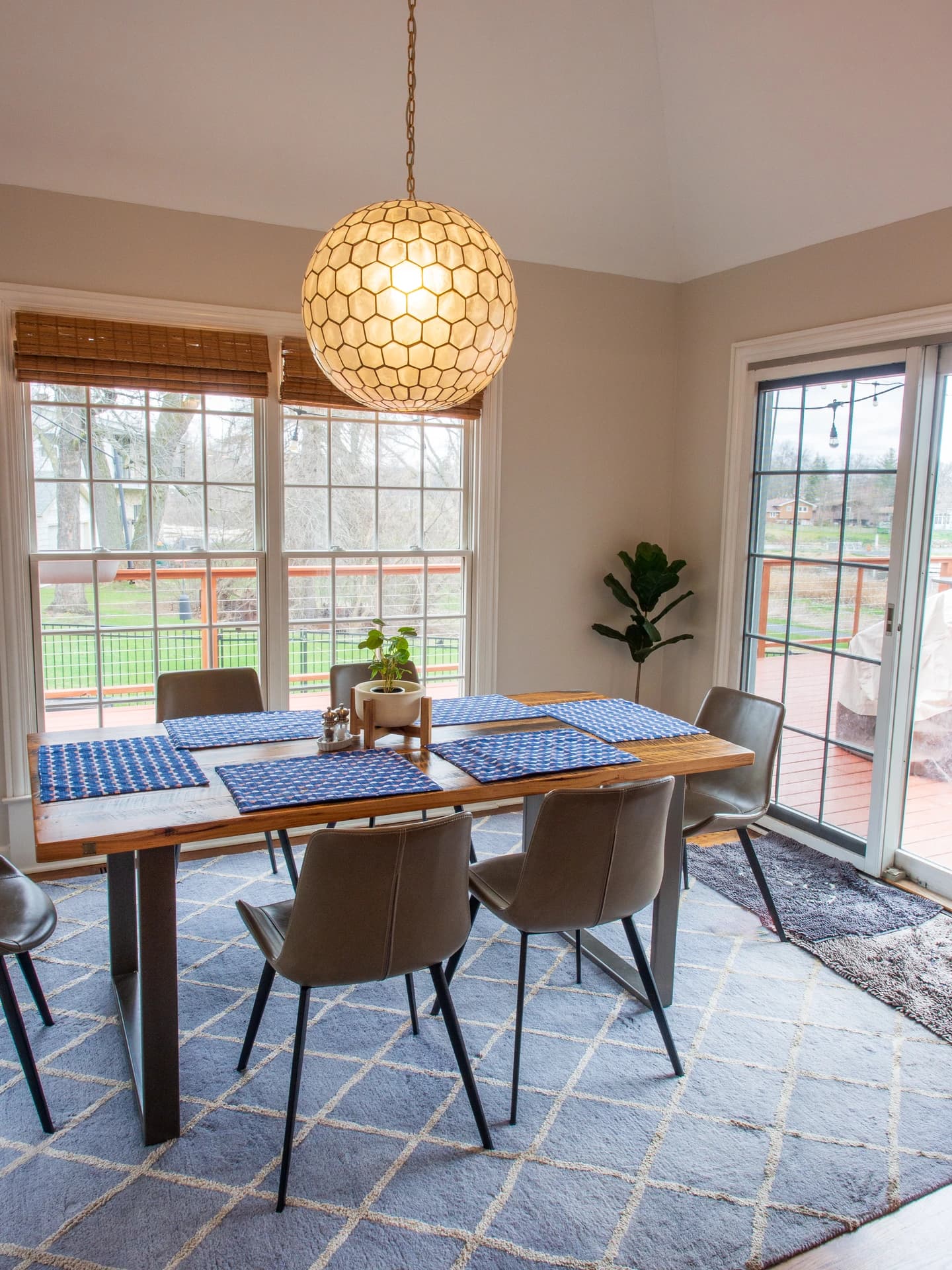 Large, modern dining room with wood floor and furniture, blue accents, and a chandelier.